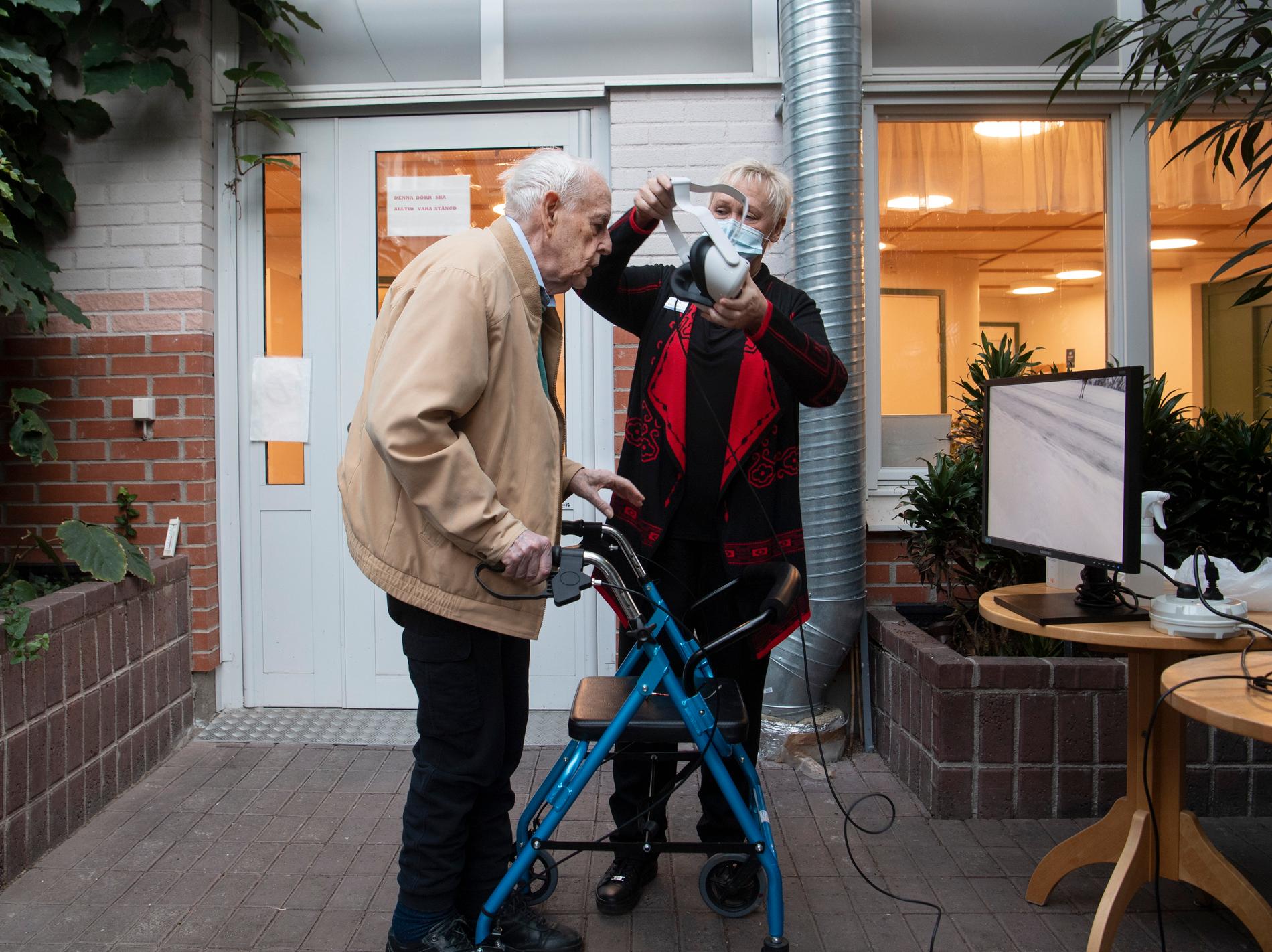 Undersköterska Lotta Andréasson hjälper Gilbert Ljunggren att möta valar under vatten med hjälp av VR-glasögon.