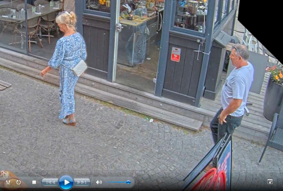 Jeanette, 61 år, har en blå och vit klänning på sig och sandaler på fötterna när hon fångas av en över­vaknings­kamera i centrala Hudiksvall. Efter henne går hennes sambo Mikael Eriksson. Några timmar senare är Jeanette död.