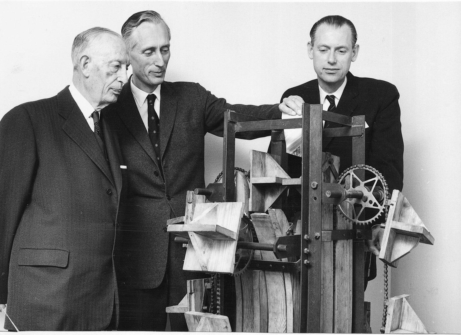 Ruben Rausing med sönerna Gad Rausing och Hans Rausing står vid en modell av tetrapackmaskinen.