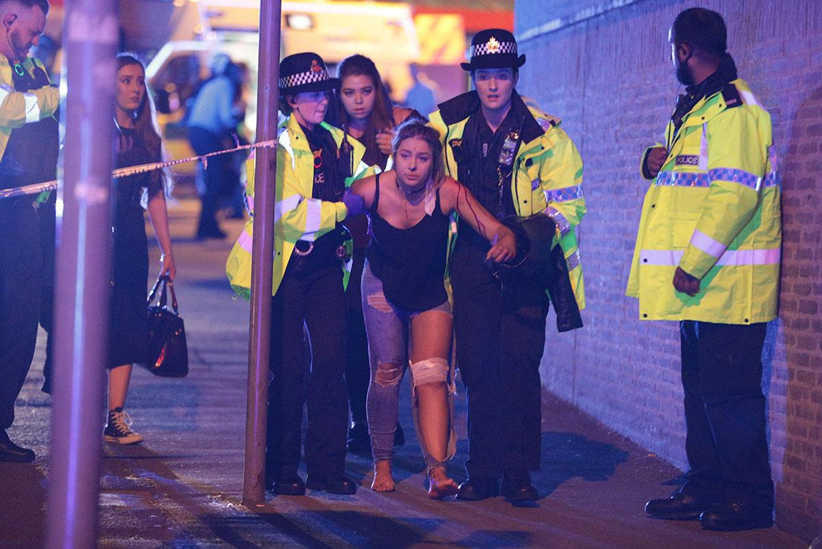 En skadad kvinna hjälps ut från Manchester Arena efter attacken. 