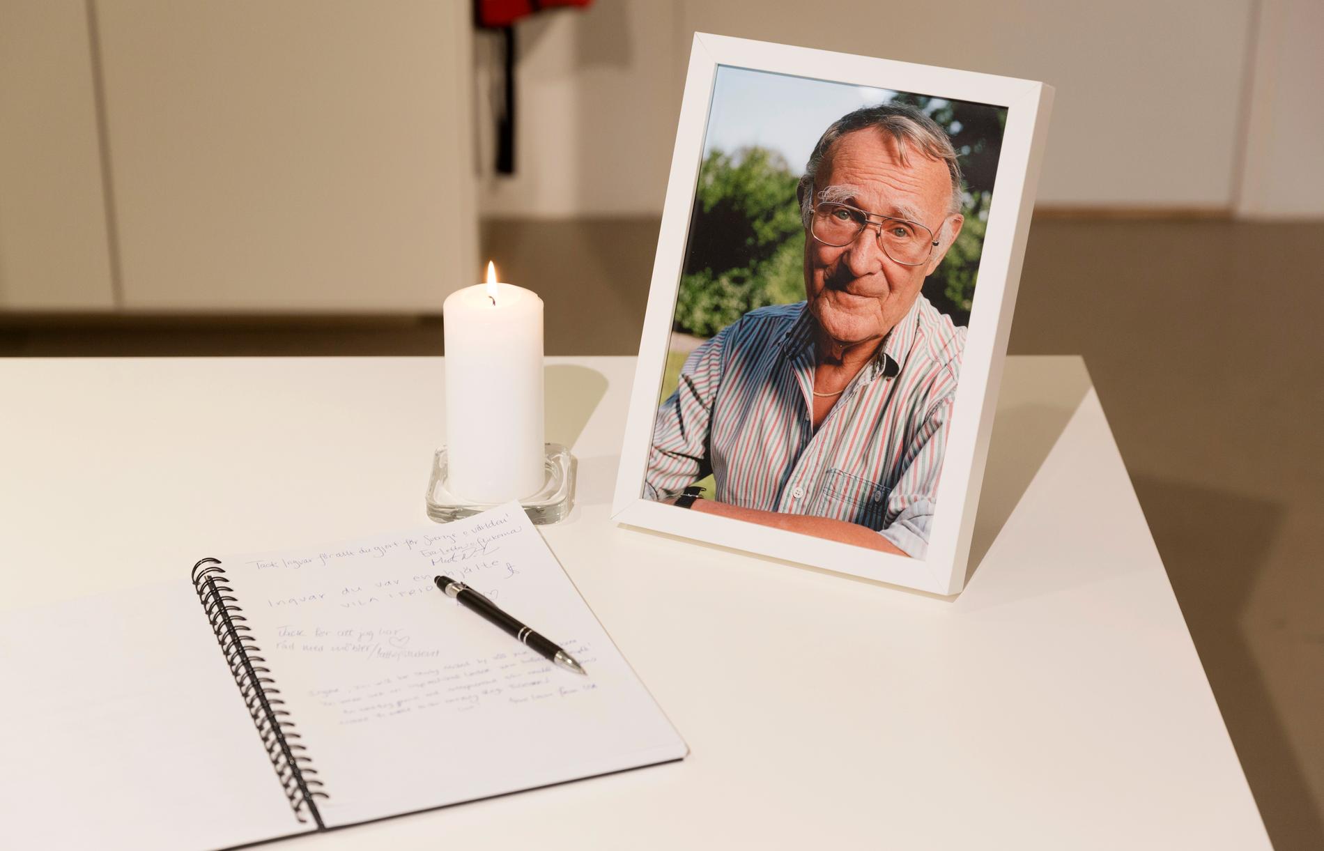 En kondoleansbok bredvid ett tänt ljus och ett fotografi på Ingvar Kamprad framställt på Ikea museet i Älmhult.