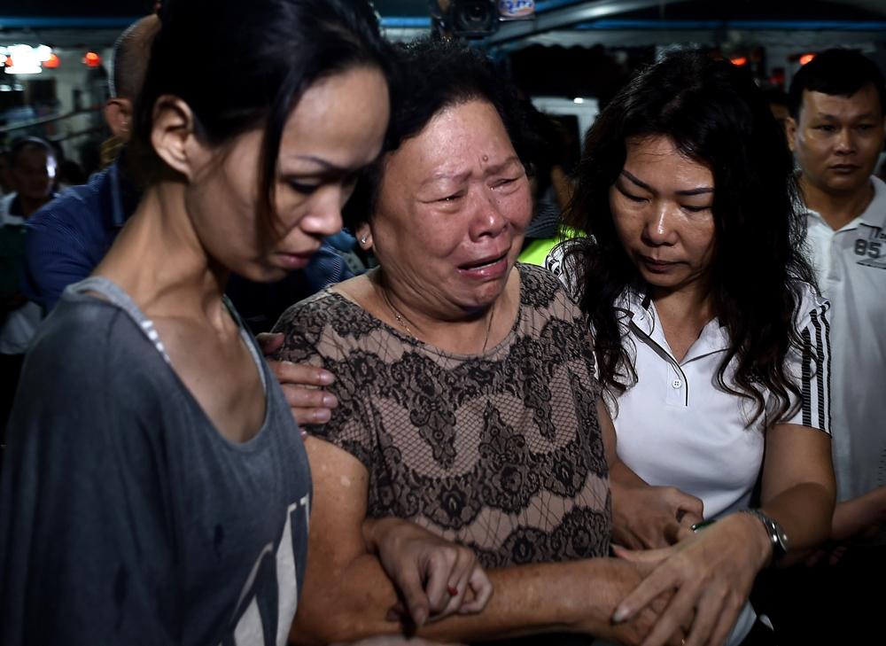 Familjemedlemmar till Neoh Hock Guan, en överlevare från Malaysia, bryter ihop vid offrens kistor efter terrordådet i Bangkok.
