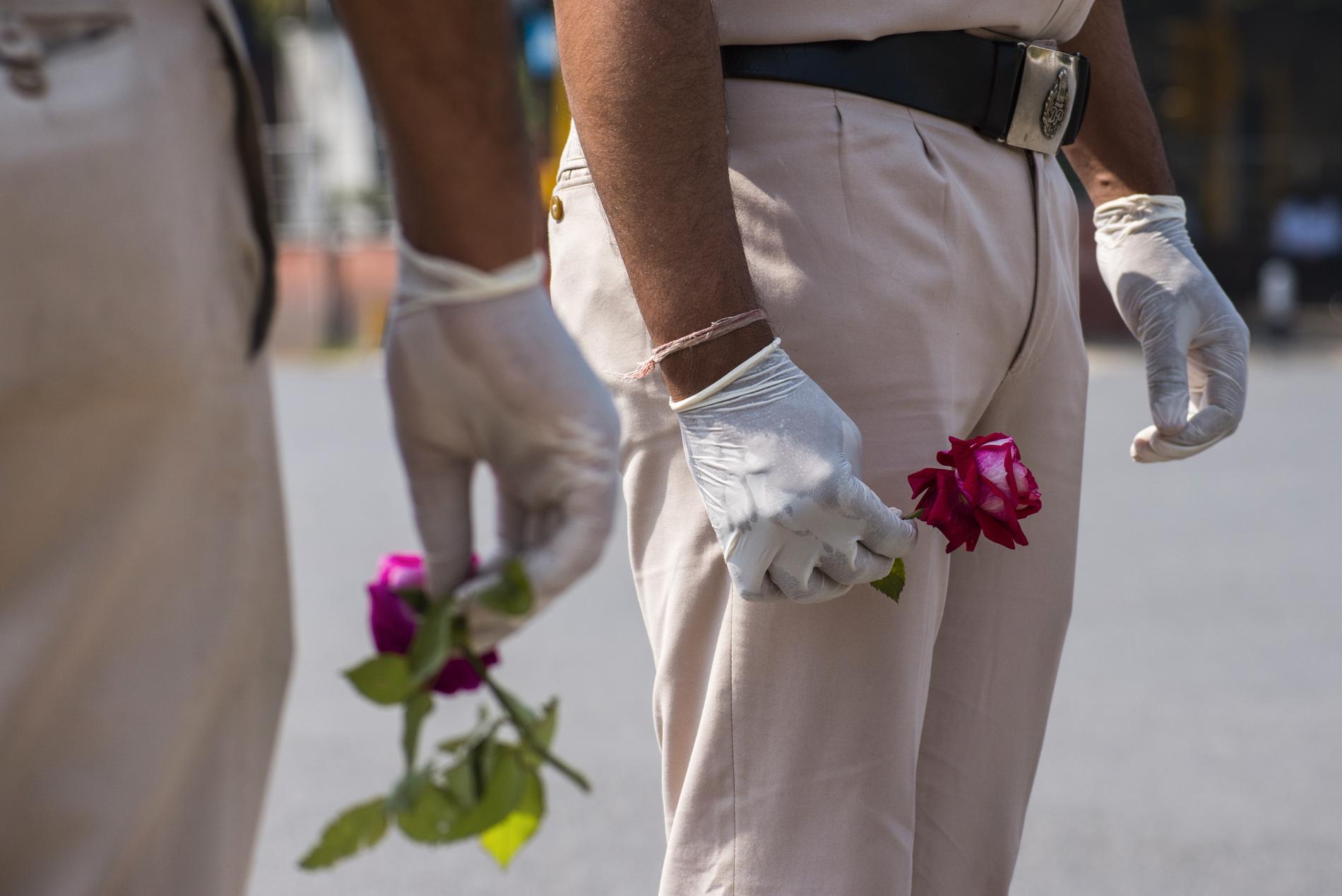 NEW DELHI, INDIEN Poliser bär rosor att ge till folk för att få dem att stanna hemma, New Delhi i söndags.