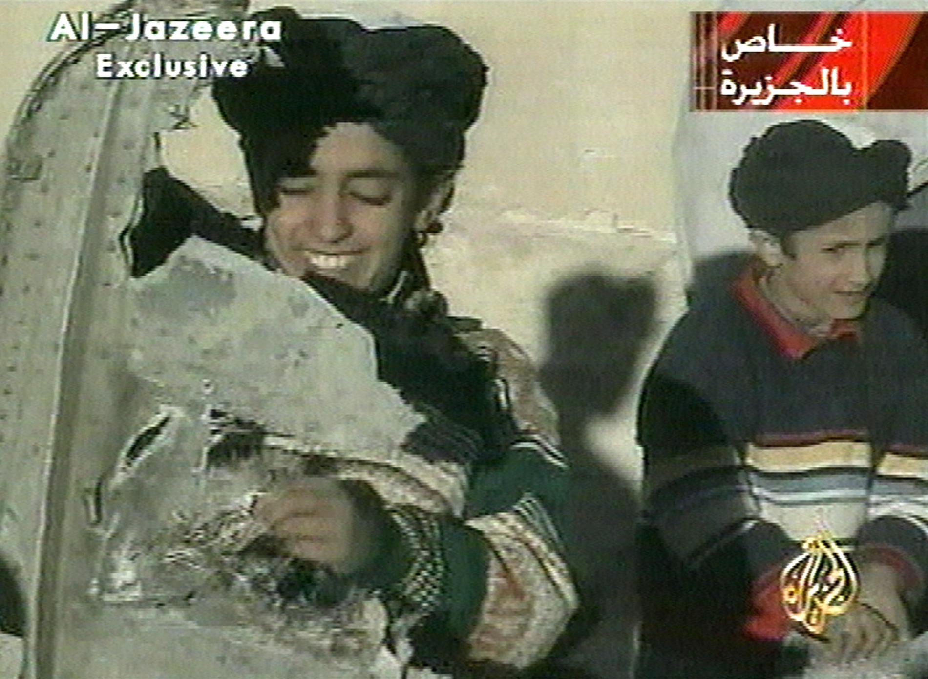 En ung Hamza bin Ladin (till vänster) håller i vad som tros vara en bit av vraket av en helikopter. Arkivbild.