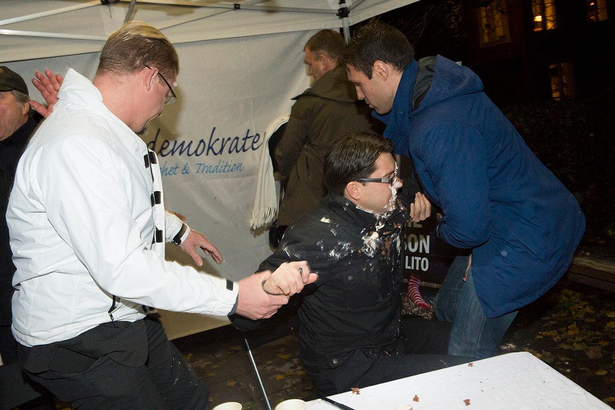 Jimmie Åkesson får en tårta i ansiktet under en boksignering, vid Nytorget i Stockholm.