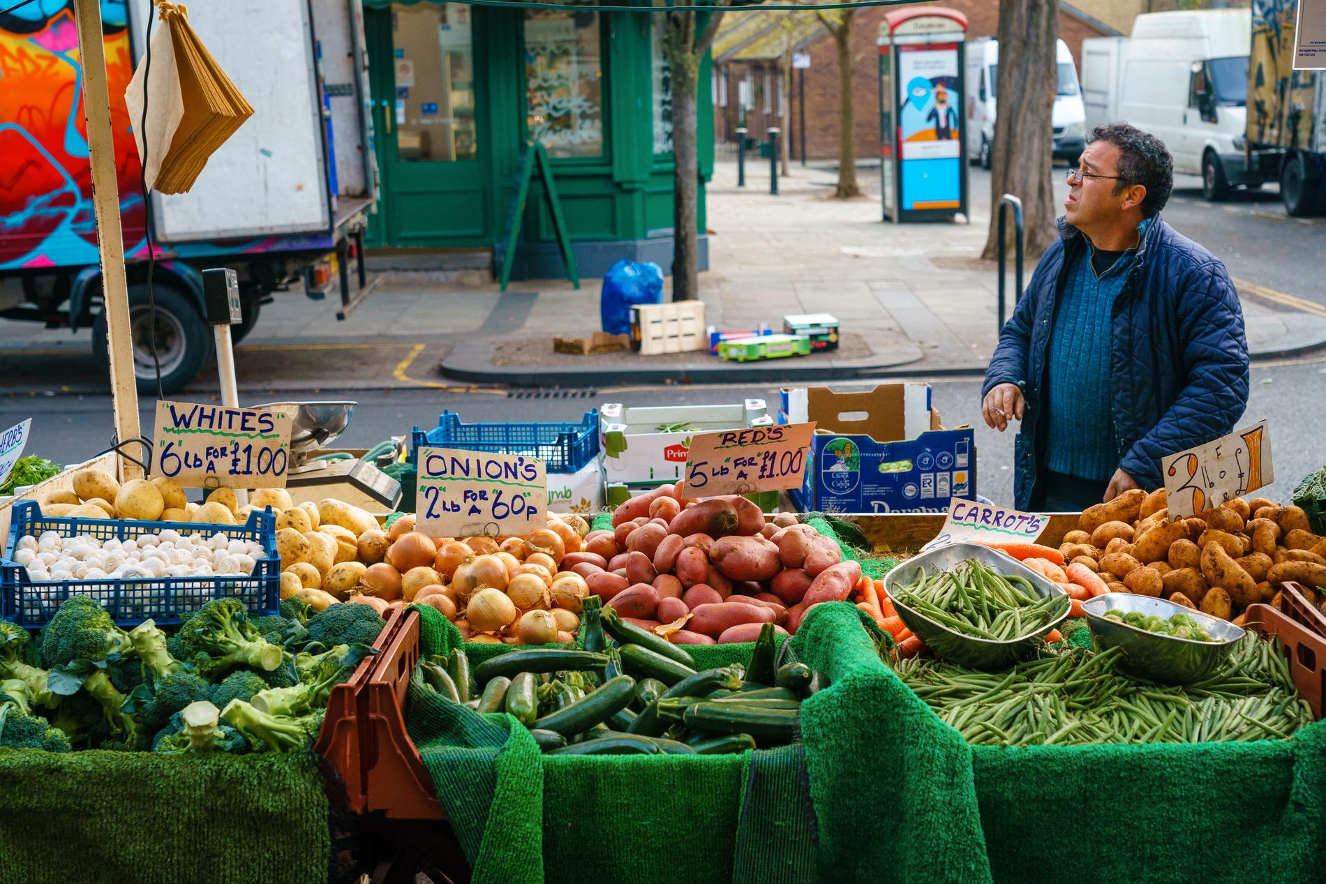 Frukt- och grönsaksförsäljarna ropar ut sina priser längs huvudgatan i Kensington. 