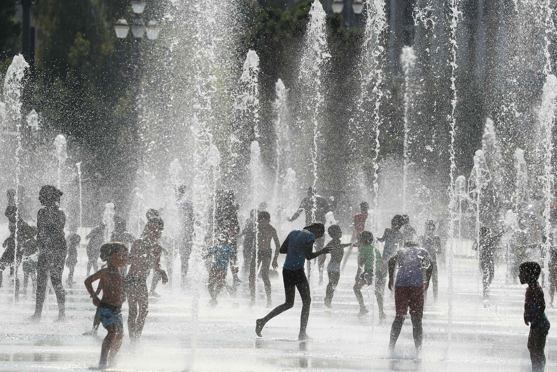 Människor svalkar sig vid en fontän i Nice, Frankrike på tisdagen. Nu väntas högre temperaturer till helgen.