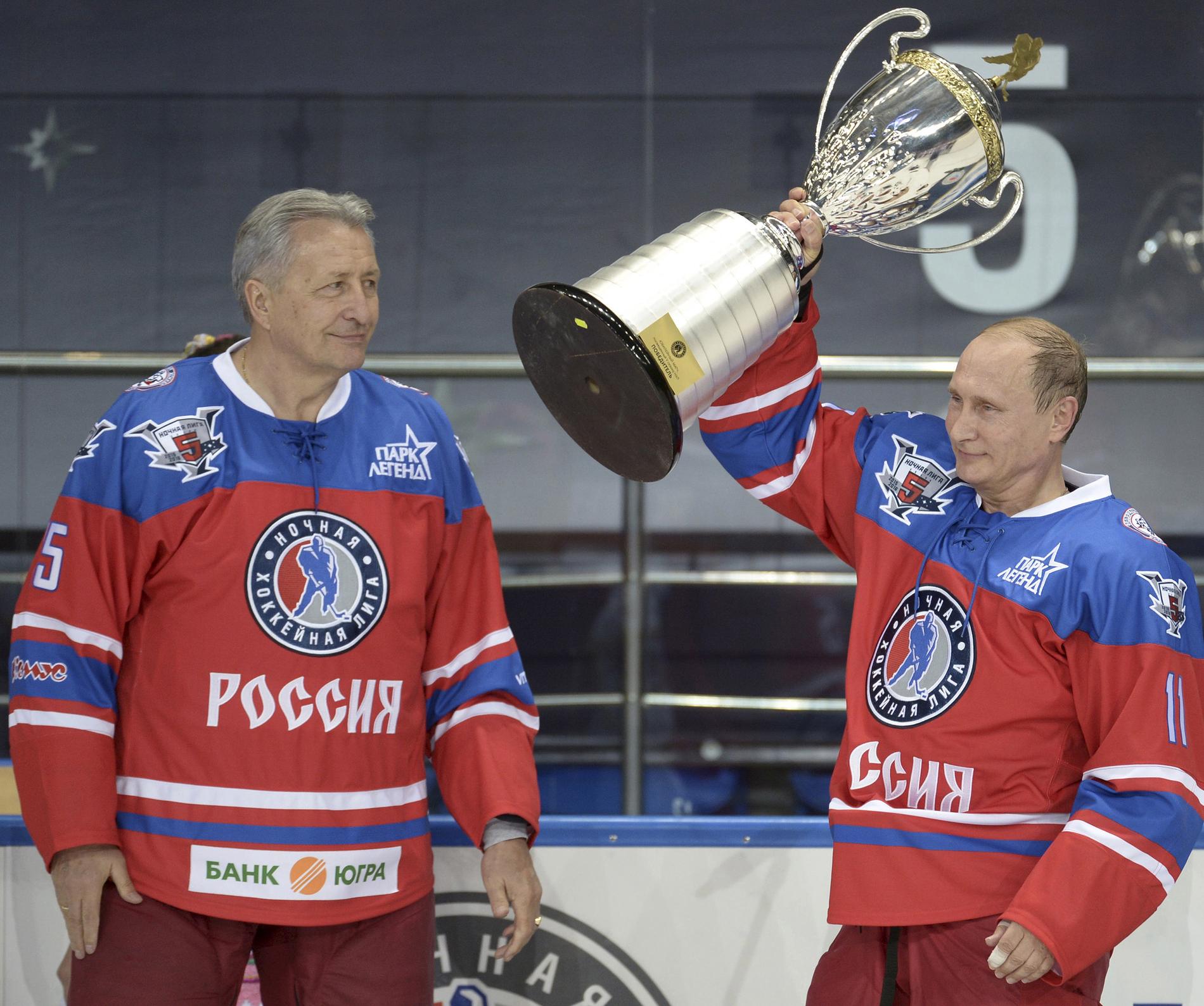 President Vladimir Putin lyfter trofén efter att ha vunnit en galamatch i Sochi onsdagen den 7 oktober 2015. Till vänster den gamel hocvkeyspelaren Alexander Yakushev.
