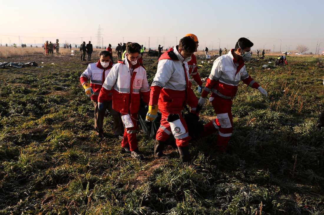 Räddningsarbetare bär bort offren från platsen där det ukrainska planet kraschade i Shahedshahr i Iran.