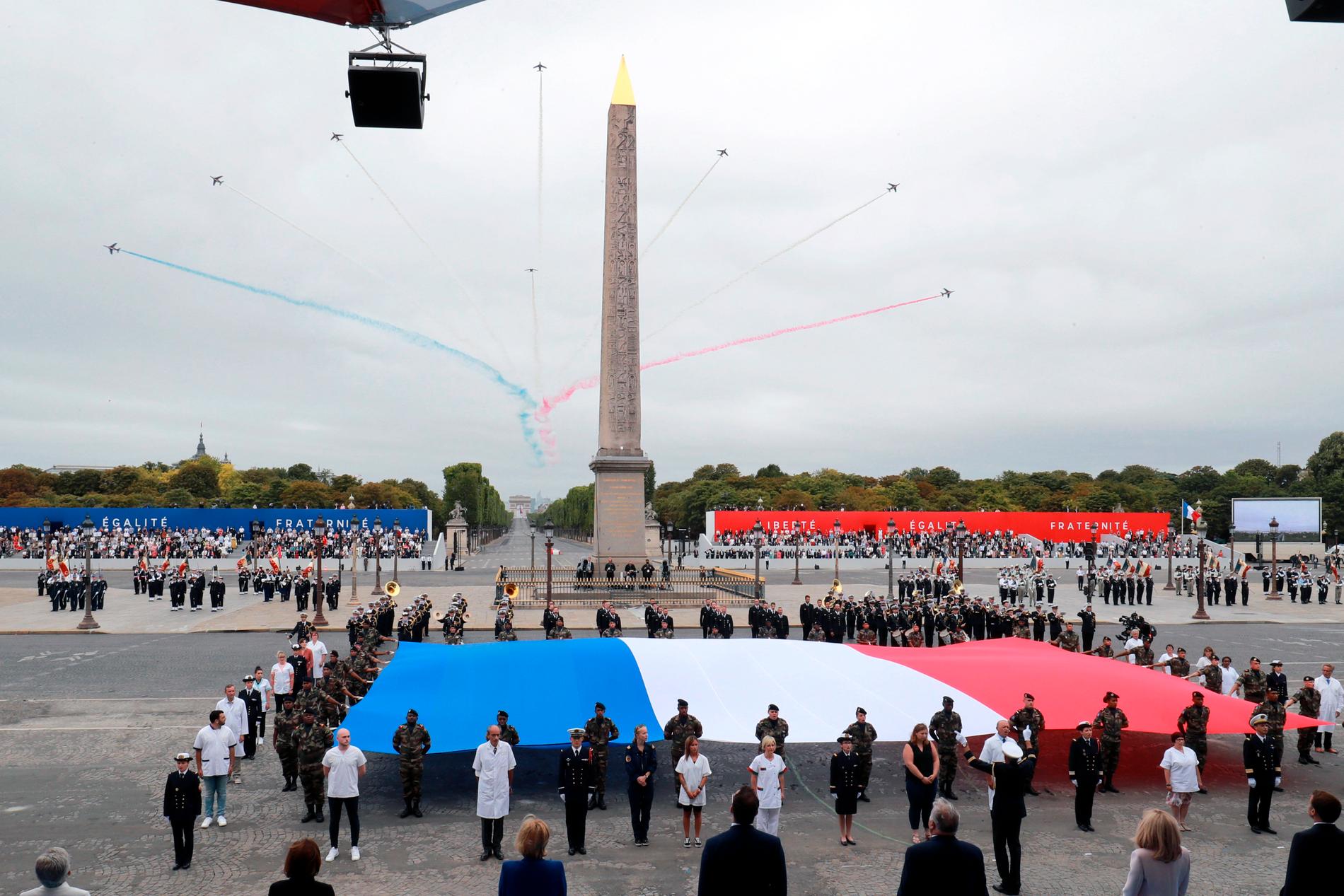 Vårdanställda tog plats vid den franska flaggan under årets decimerade nationaldagafriande vid Place de la Concorde i Paris.