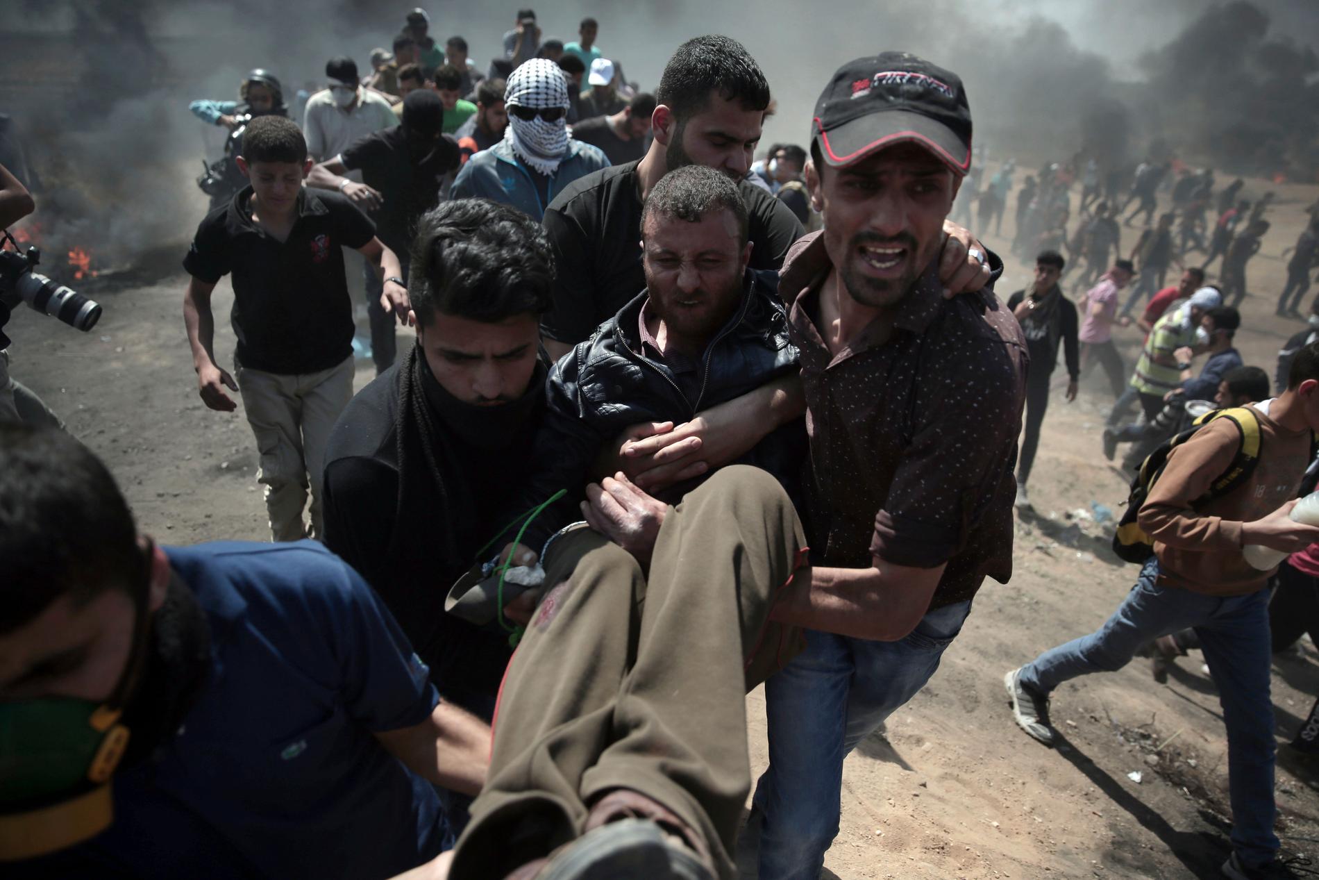 En skottskadad palestinier bärs undan av andra demonstranter vid protesterna på Gazaremsan.