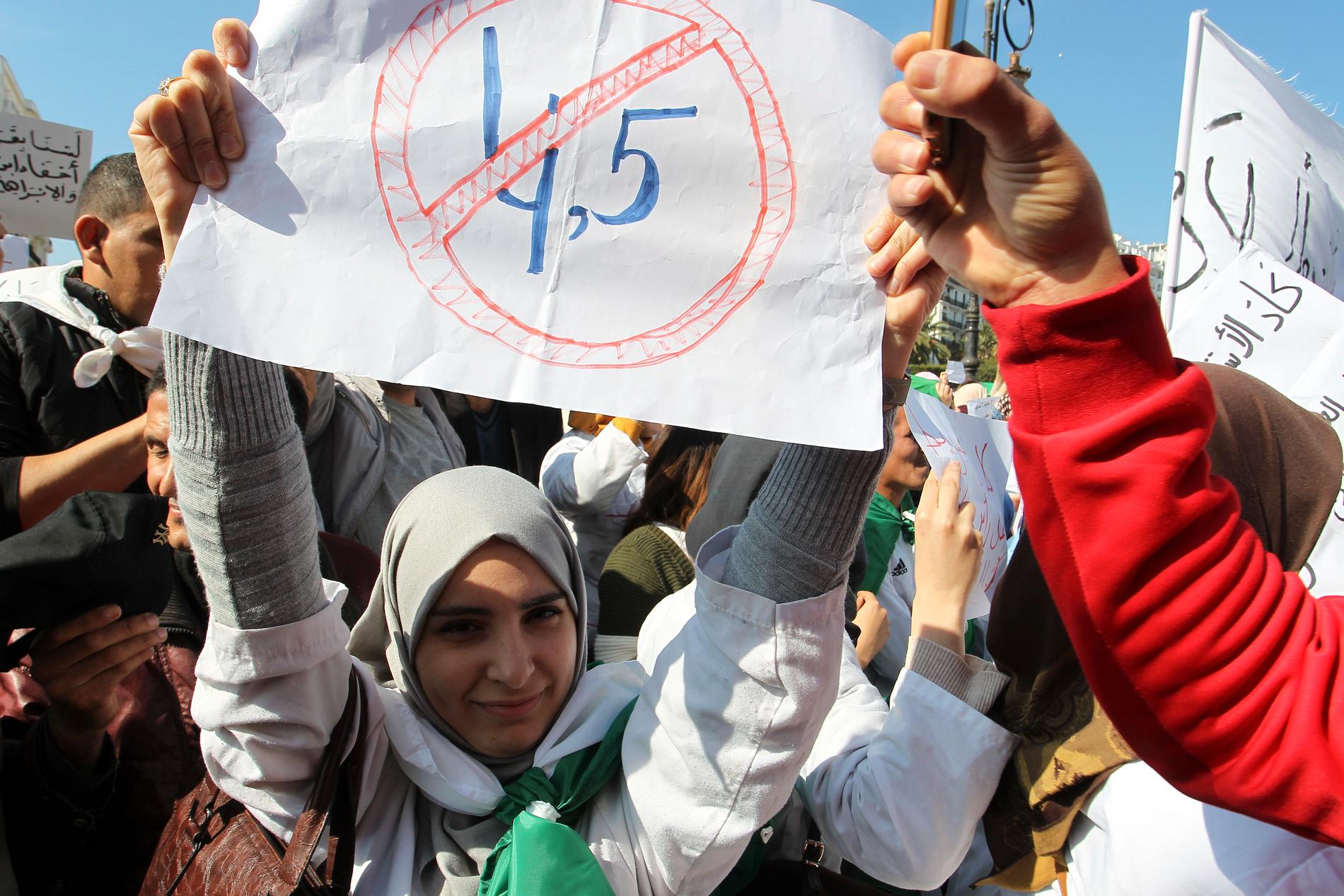En strejkande lärare håller fram en skylt i Alger på torsdagen. Tidigare skyltar med en överstruken femma (som i en femte mandatperiod) har ersatts av "4,5" (en förlängd fjärde mandatperiod).