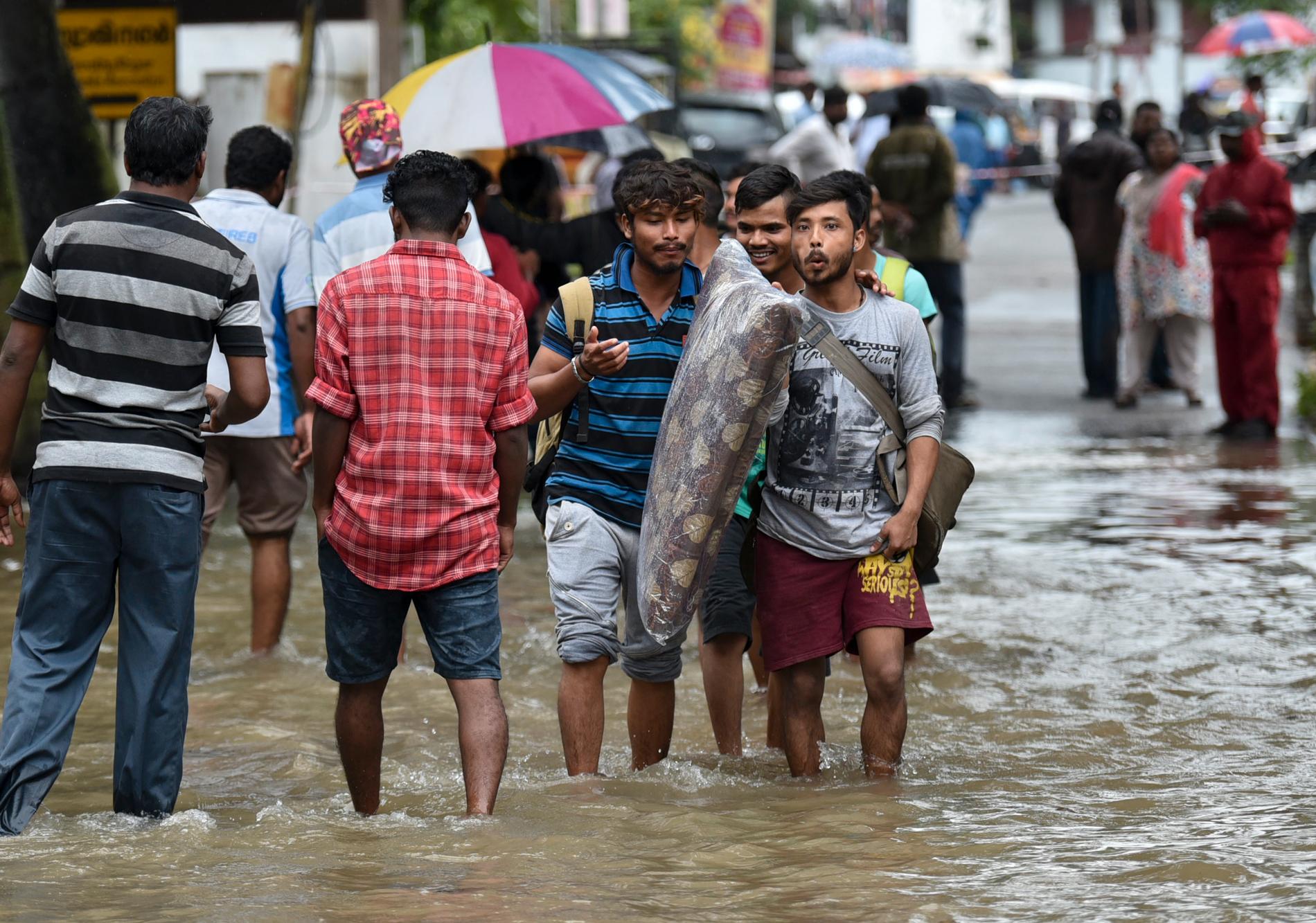 Människor på väg hem från arbetet vadar igenom översvämmade gator i Thiruvananthapuram i delstaten Kerala i Indien.