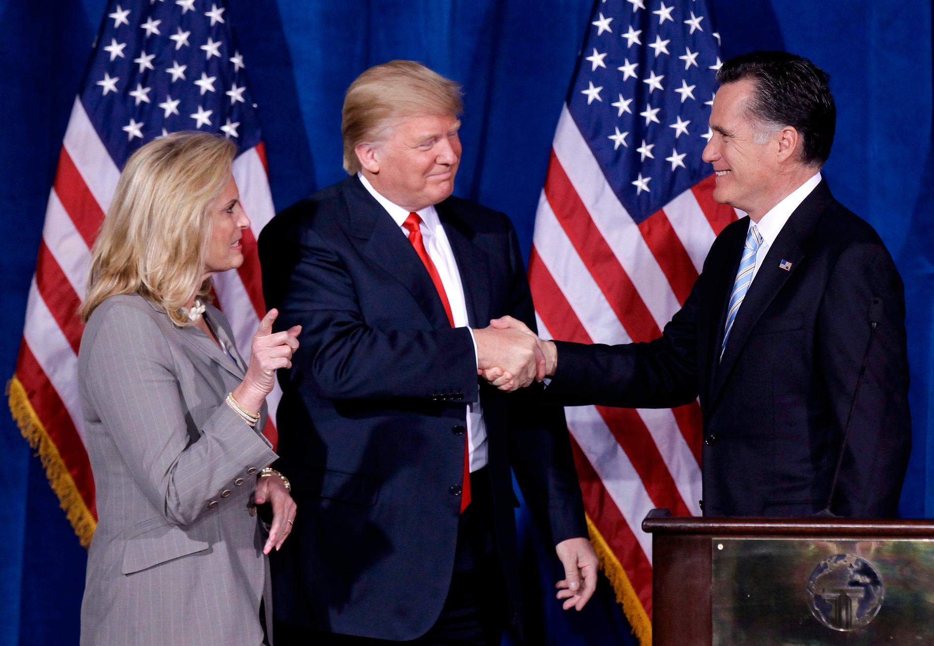Dåvarande affärsmannen Donald Trump hälsar på Mitt Romney, efter att ha ställt sig bakom republikanens presidentkandidatur i februari 2012. Till vänster står Romneys hustru Ann.