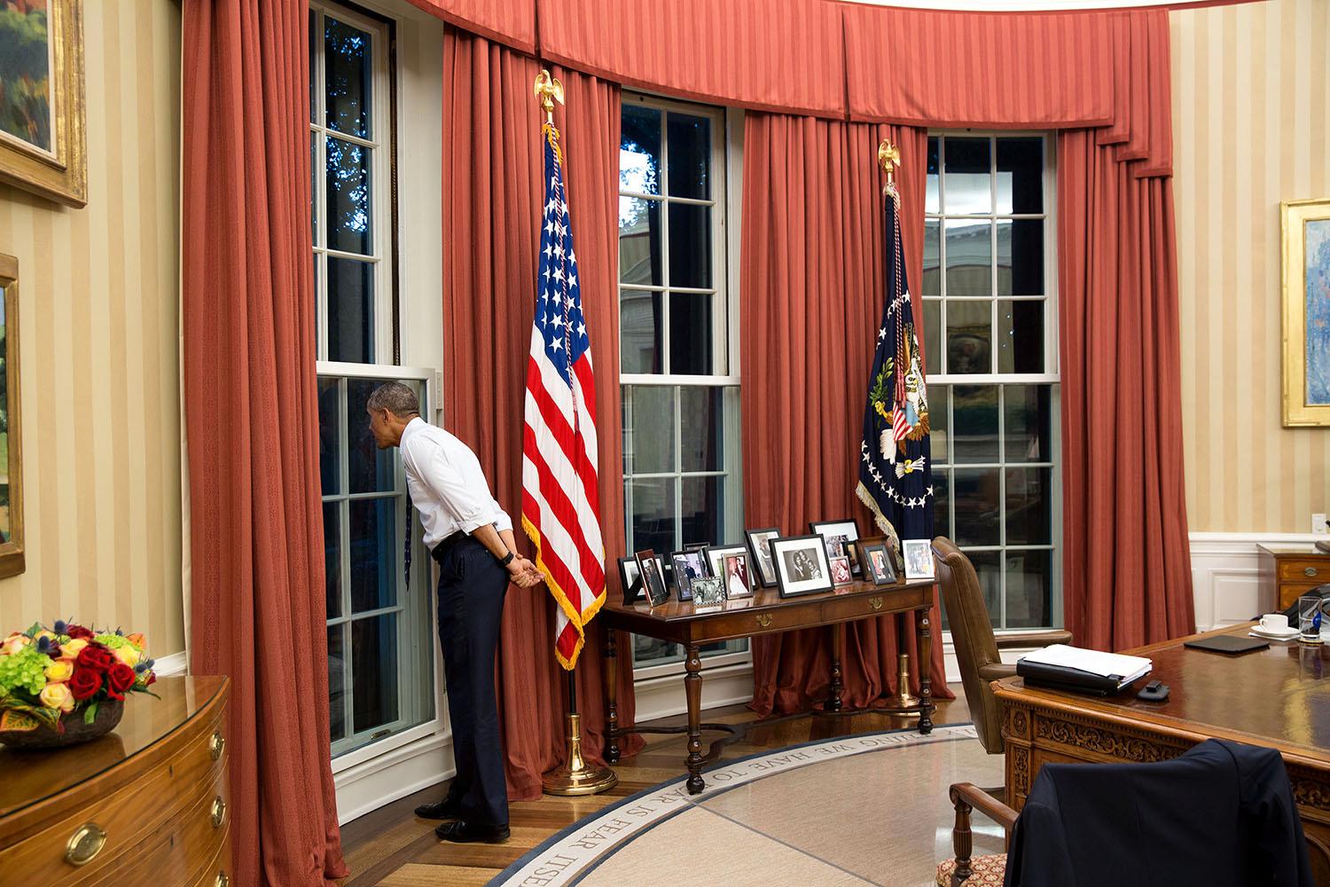 Obama tittar ut genom ett fönster i Ovala rummet samtidigt som en storm passerar utanför.