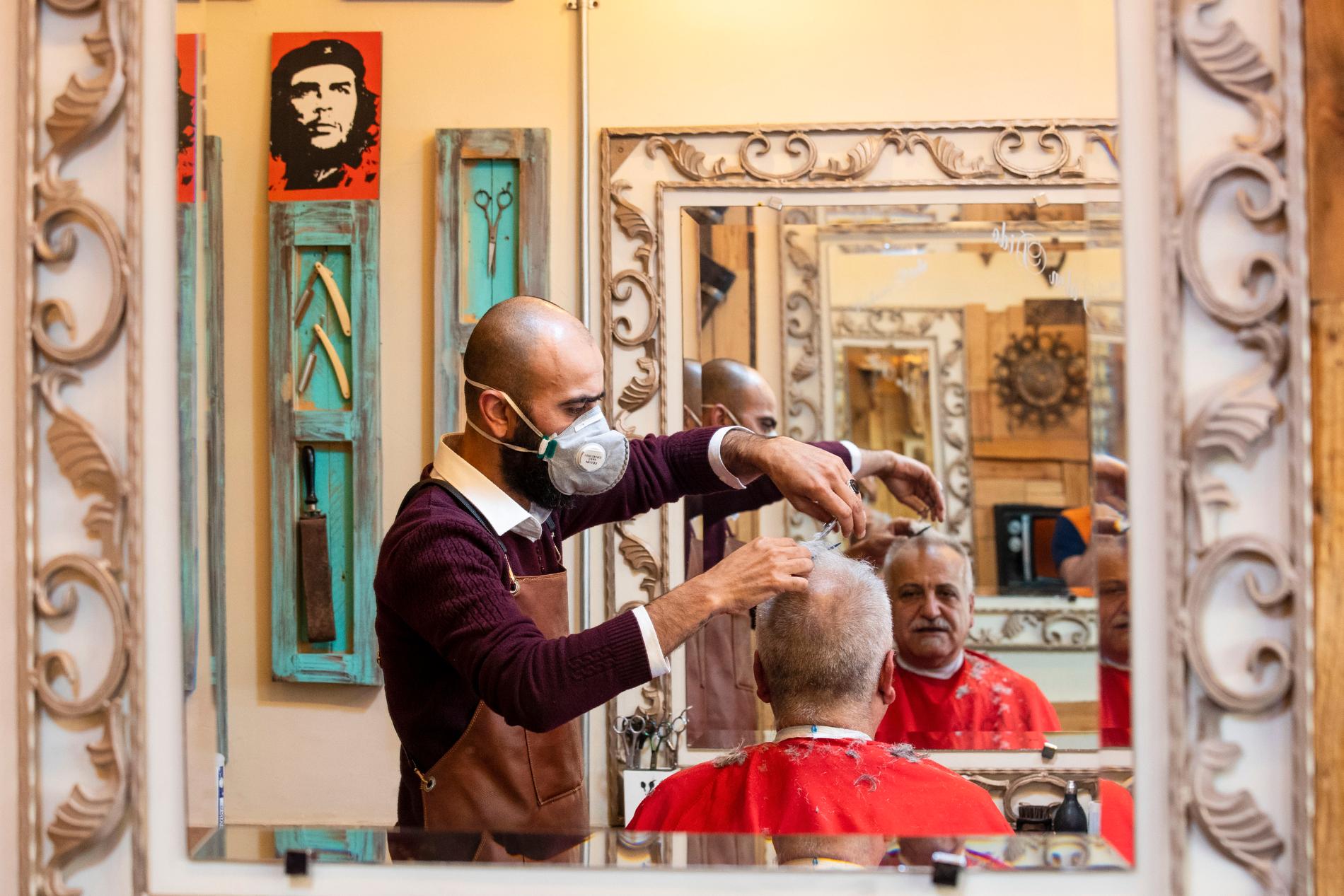 En frisör med andningsskydd klipper en kund i en salong i Libanons huvudstad Beirut i måndags. Nedstängningen av landet väntas förlängas, samtidigt som vissa restriktionslättnader tillåtit bland annat frisörer och restauranger att öppna, men till 30 procent av den normala kapaciteten.