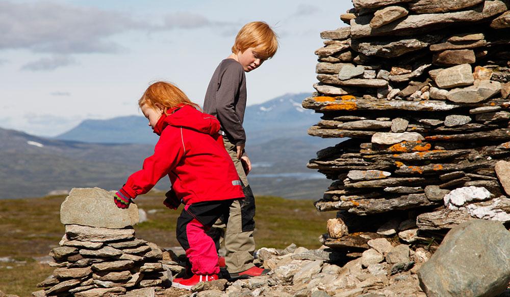 Hilda och Kalle staplar stenar under en fjällvandring kring Ramundberget.