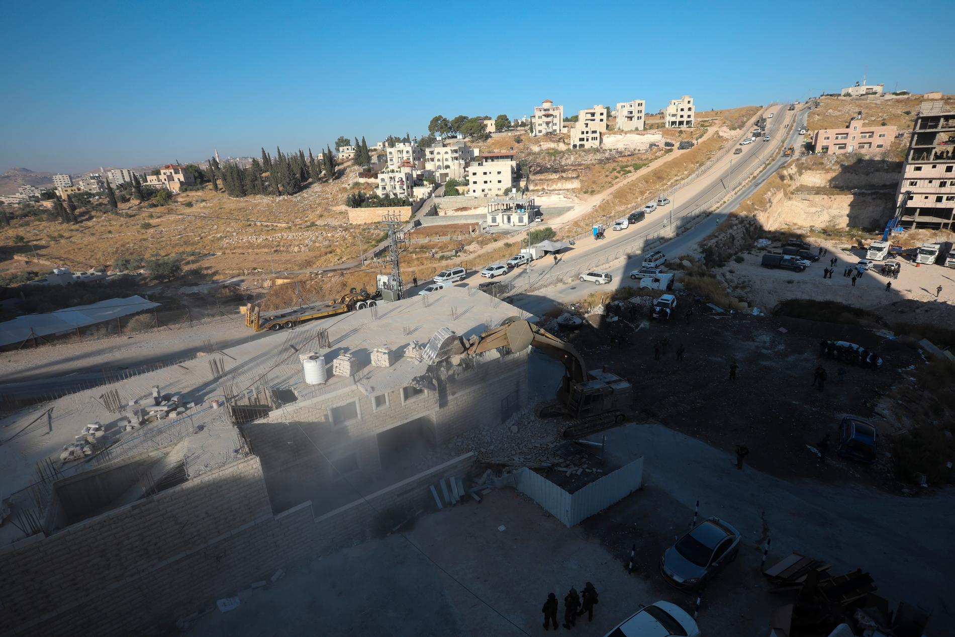 En israelisk militär bulldozer river en byggnad i en palestinsk by söder om Jerusalem.