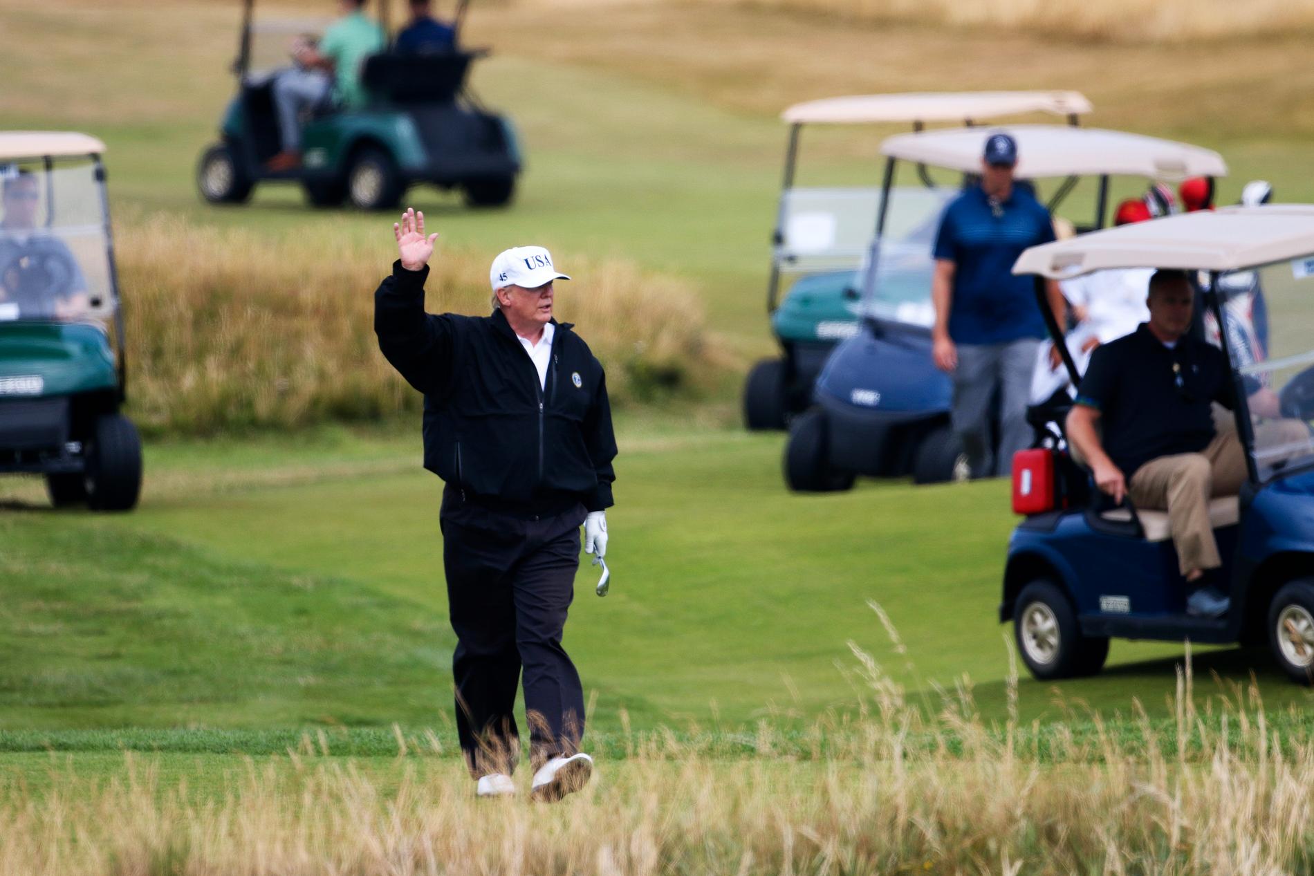 USA:s president Donald Trump vinkar till demonstranter i närheten medan han spelar golf på Trump Turnberry i Skottland.
