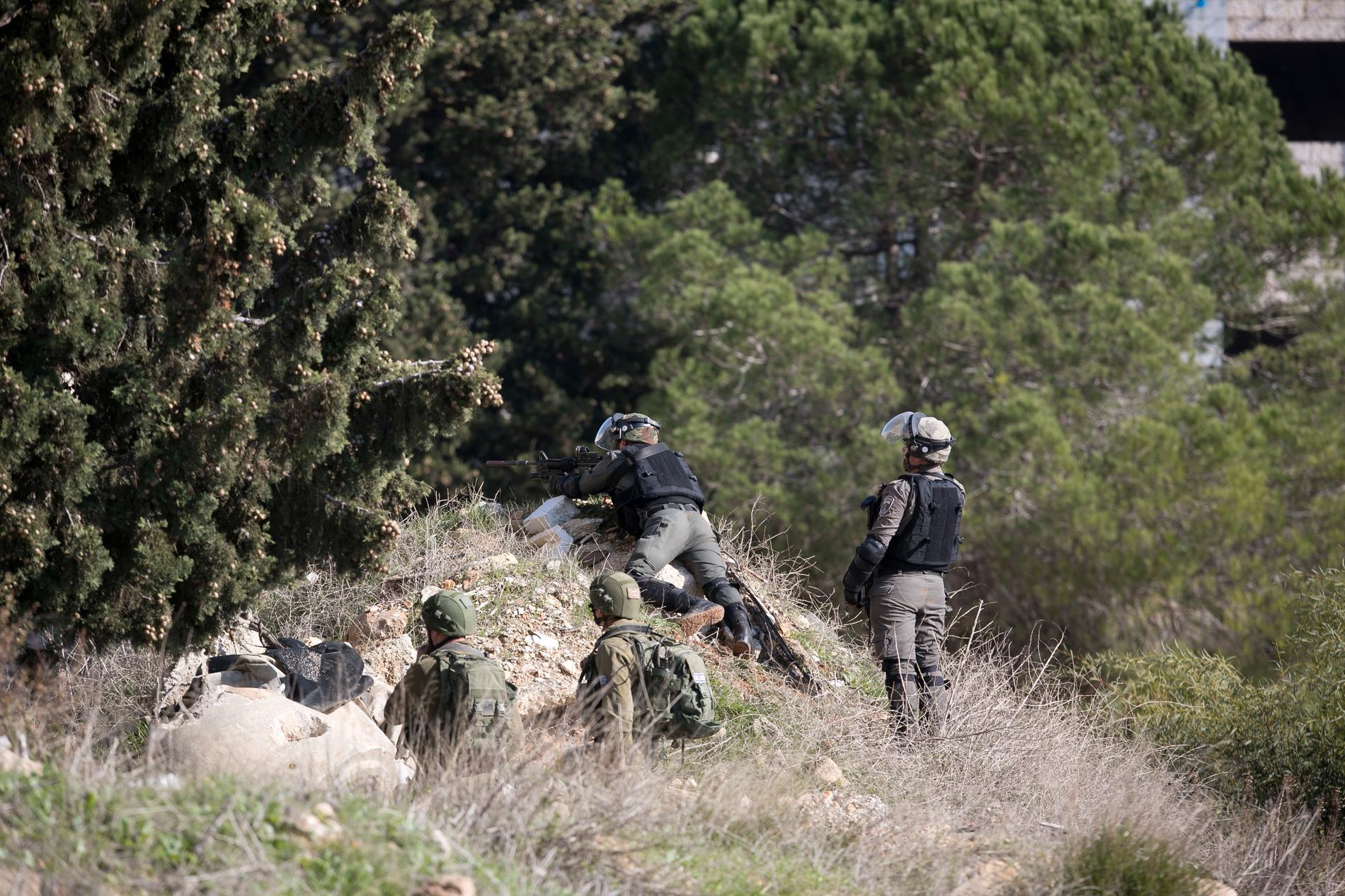 Israeliska soldater söker efter gärningsmännen som låg bakom en skottlossning vid en busshållplats nära bosättningen Ofra på den ockuperade Västbanken.