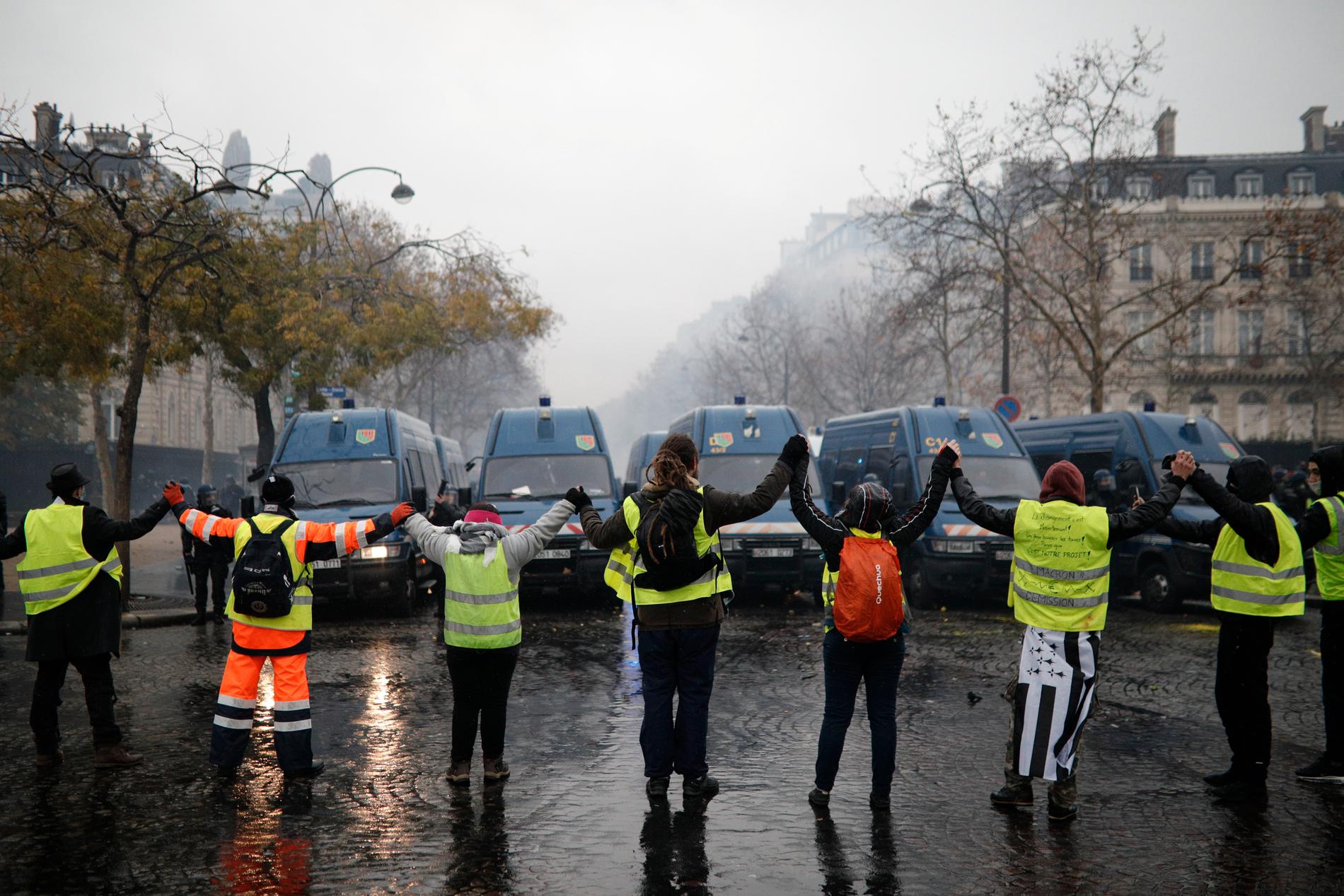 Demonstranter formar en kedja framför polisens ställningar i närheten av Champs-Élysées.