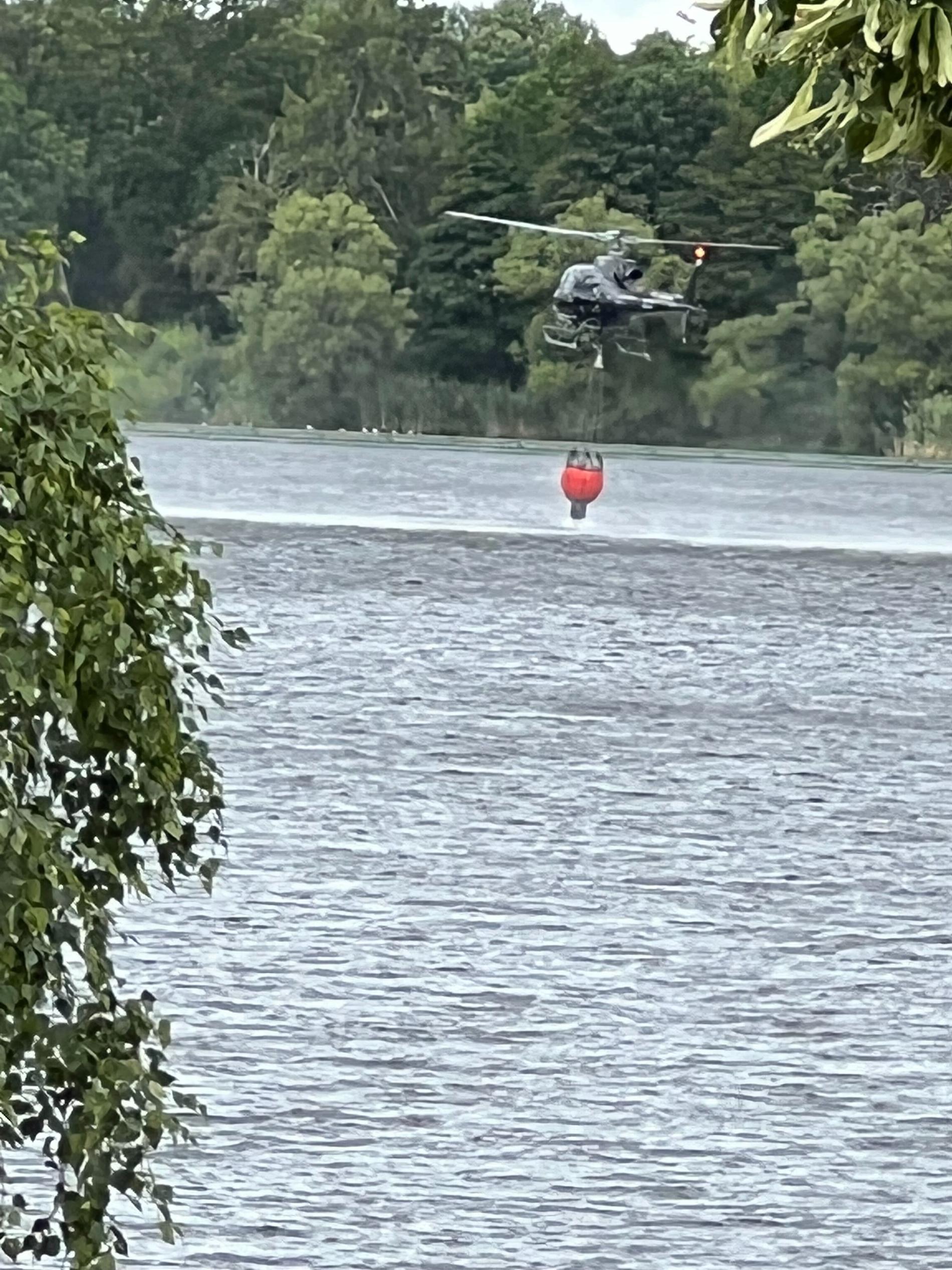 Räddningshelikoptern hämtar vatten i en sjö i närheten. 