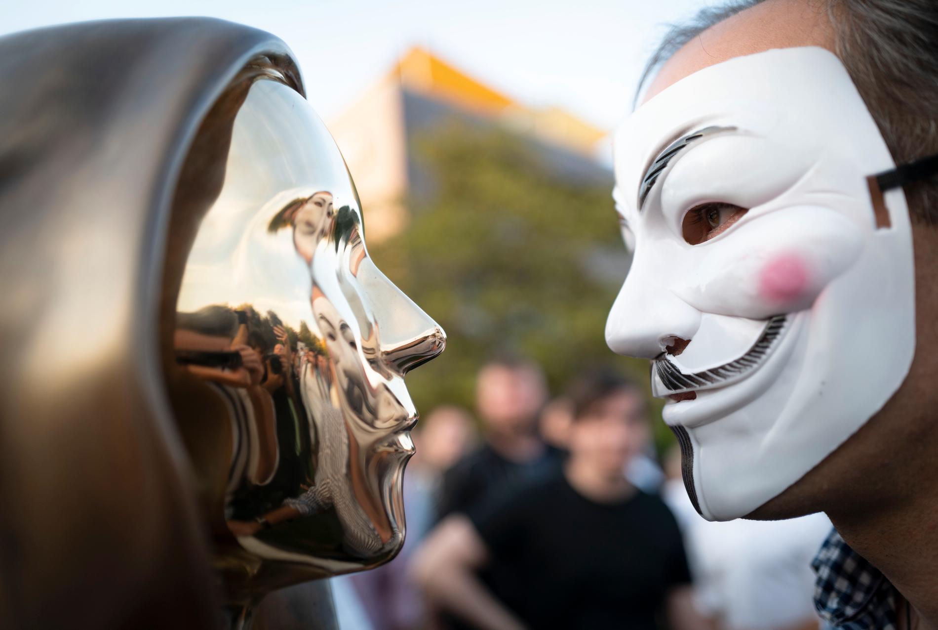En staty som ska symbolisera bitcoins grundare Satoshi Nakamoto till vänster och en person i Guy Fawkes-mask till höger. Arkivbild från ett evenemang i Budapest.