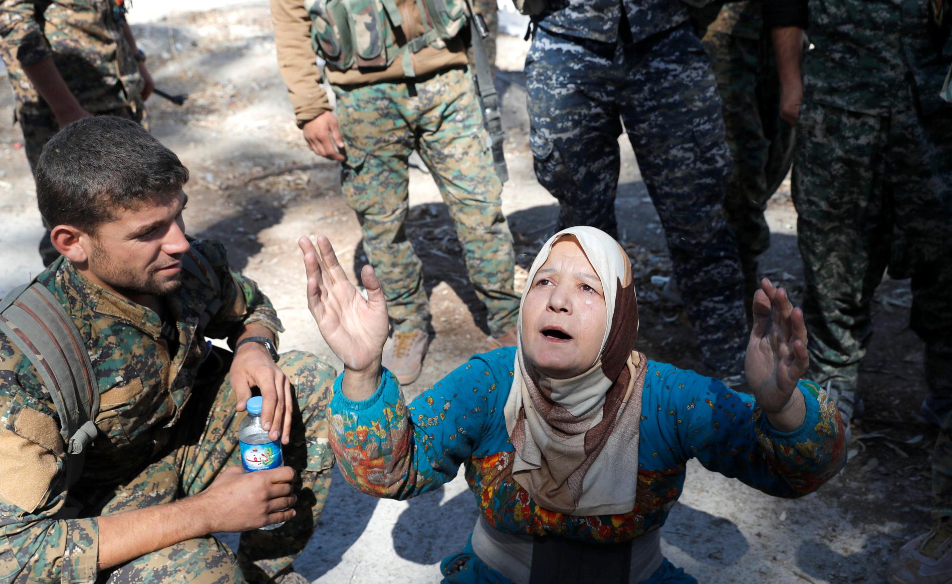 En kvinna ber efter att hennes kvarter befriats av SDF-soldater