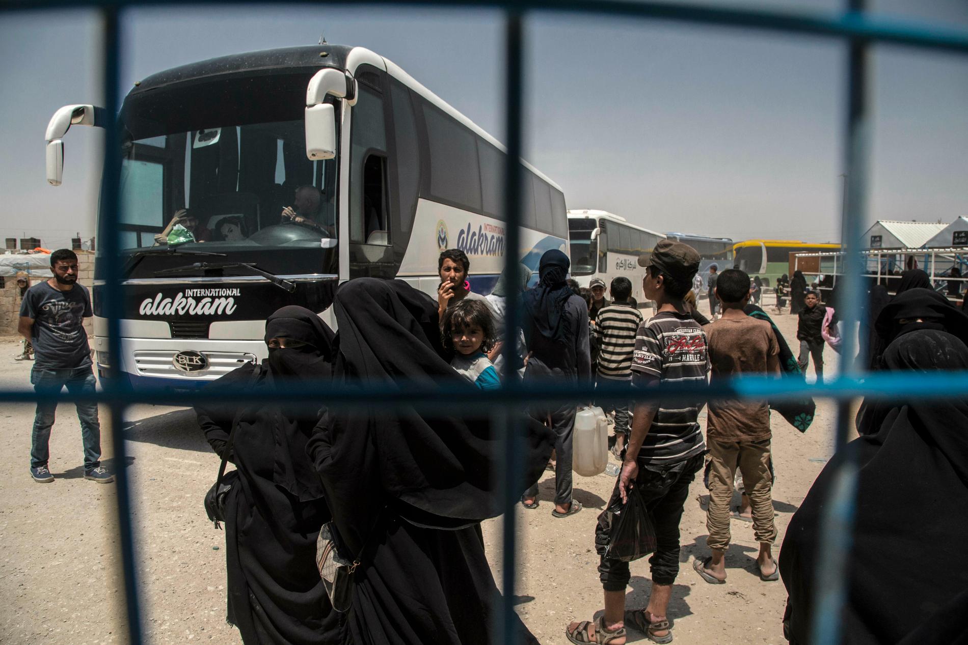 Kvinnor och barn med kopplingar till IS går på en buss för att lämna lägret al-Hol i Syrien. Arkivbild från juni 2019.