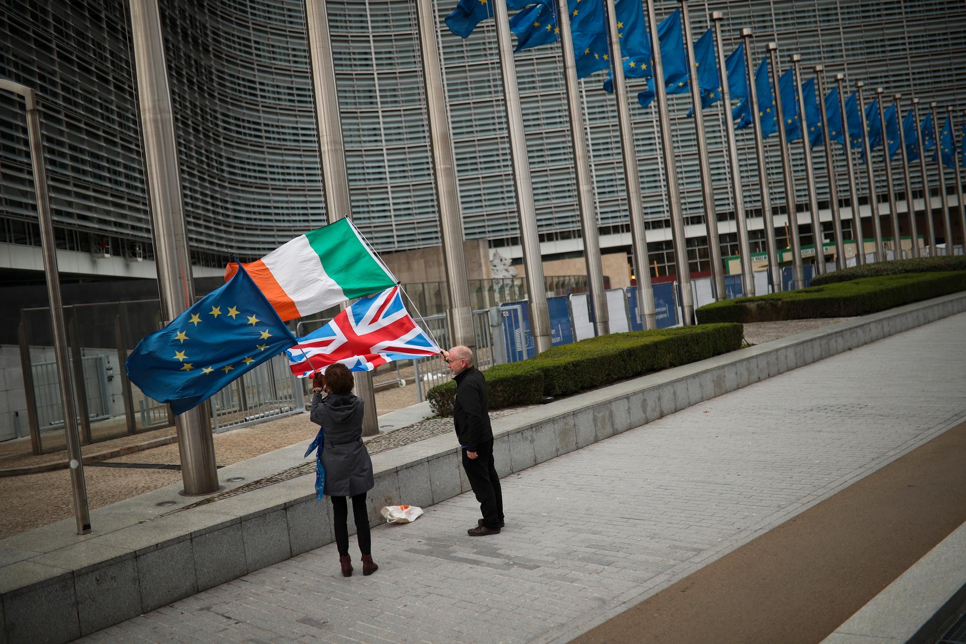 Två personer med EU:s, Irlands och Storbritanniens flaggor under brexitförhandlarnas möte i Bryssel.