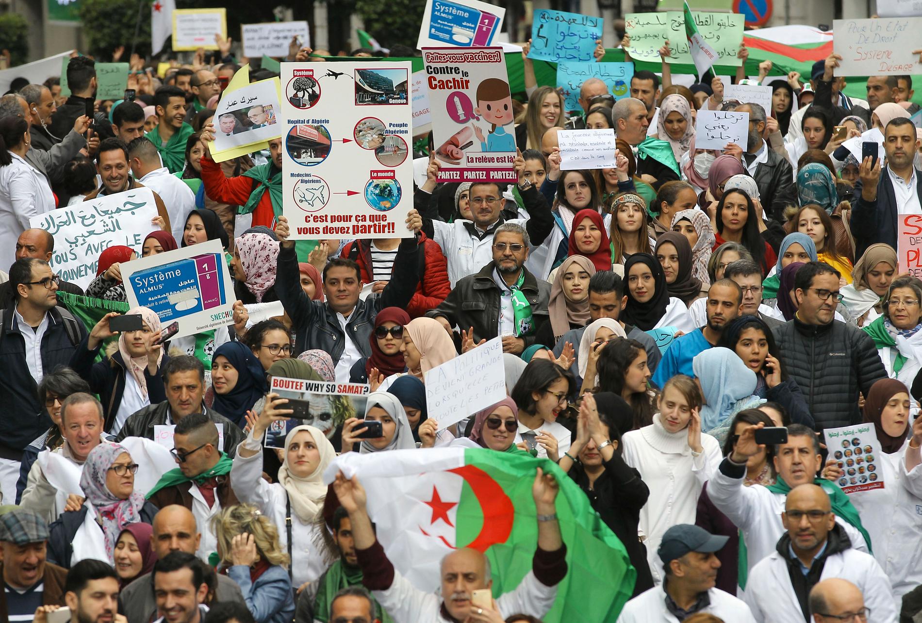 Människor demonstrerar med skyltar och flaggor under en protest i Algeriets huvudstad Alger, med krav på president Abdelaziz Bouteflikas avgång.