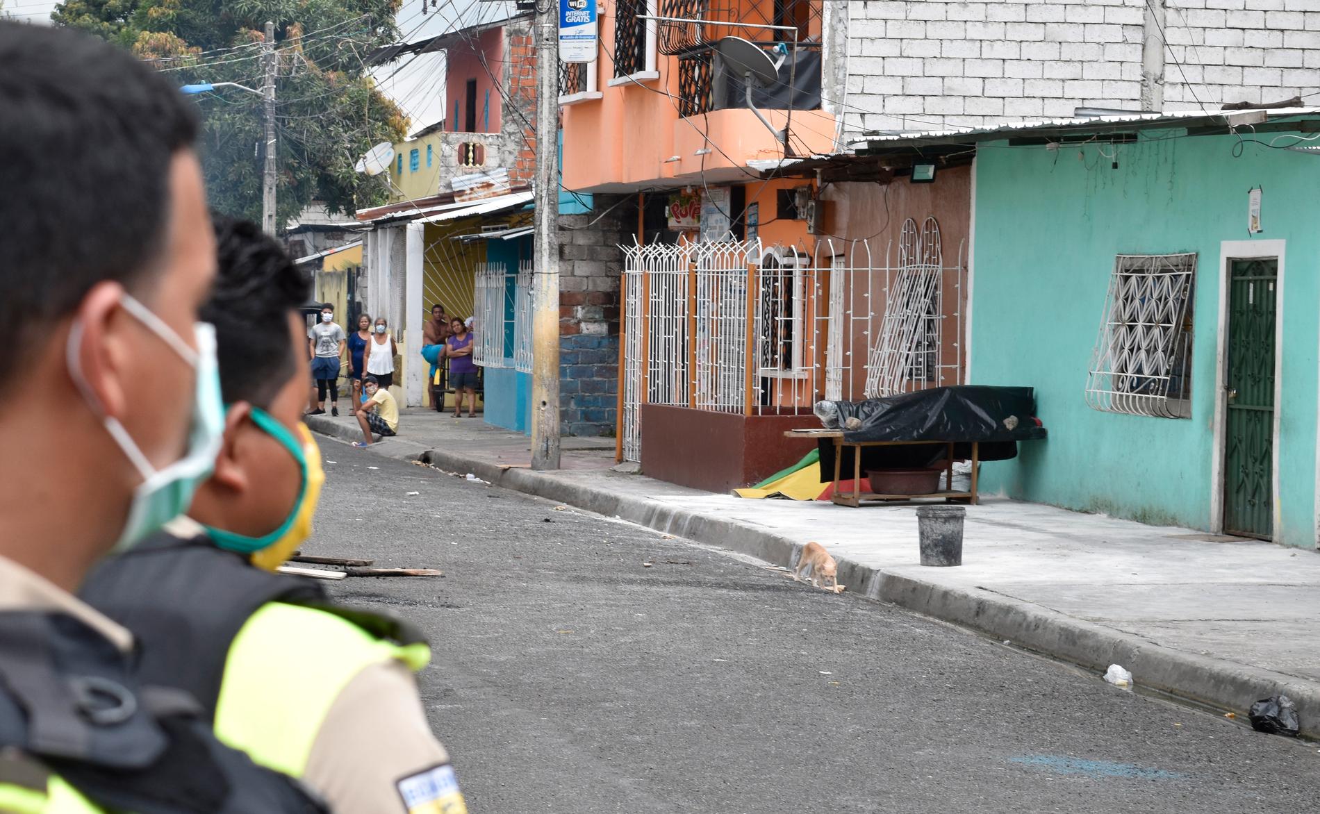 Polis vid en gata där en kropp placerats på trottoaren i Guayaquil i början av april.