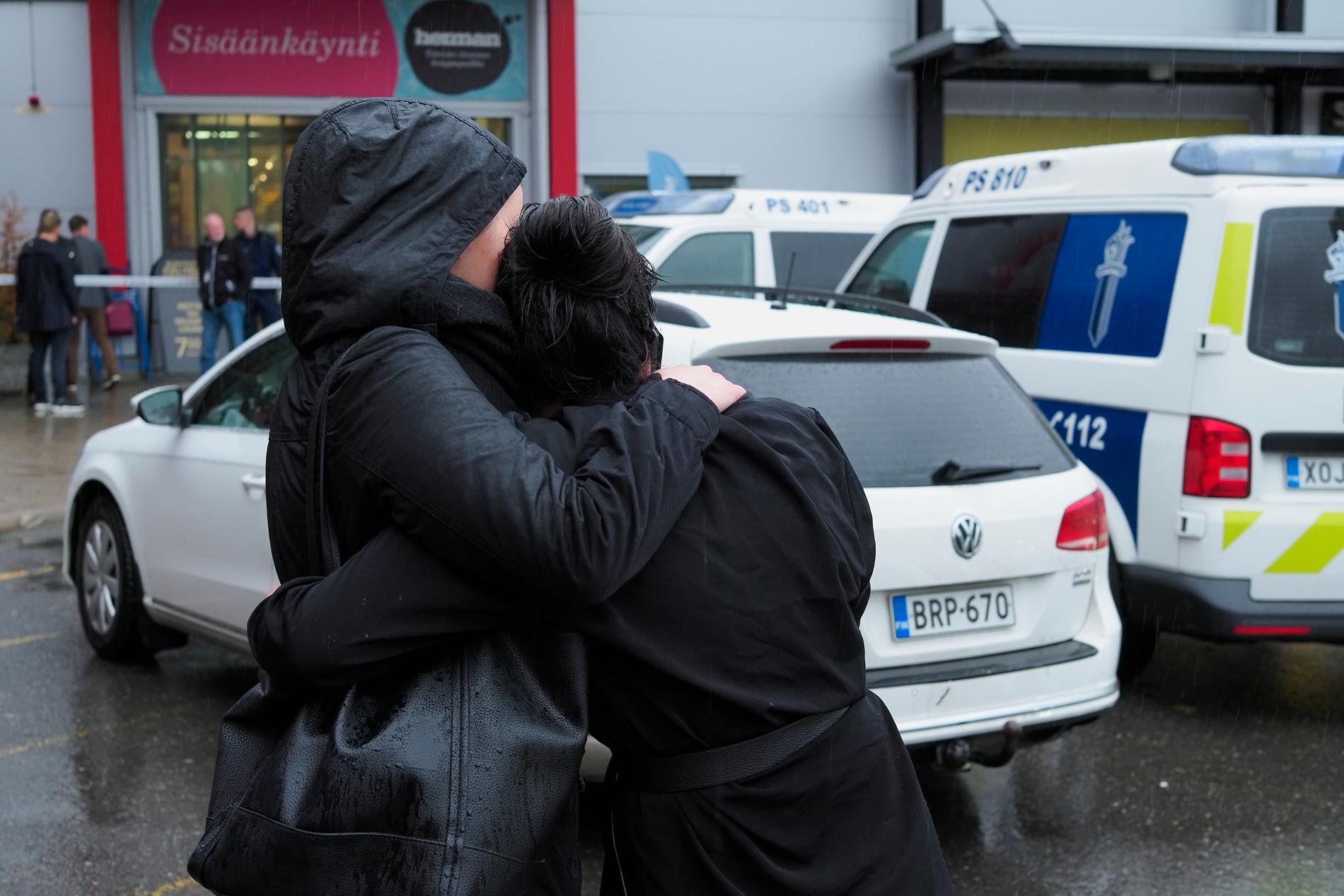 Två personer kramar om varandra utanför köpcentrumet där minst en person dödades och nio skadades i en attack på tisdagen.