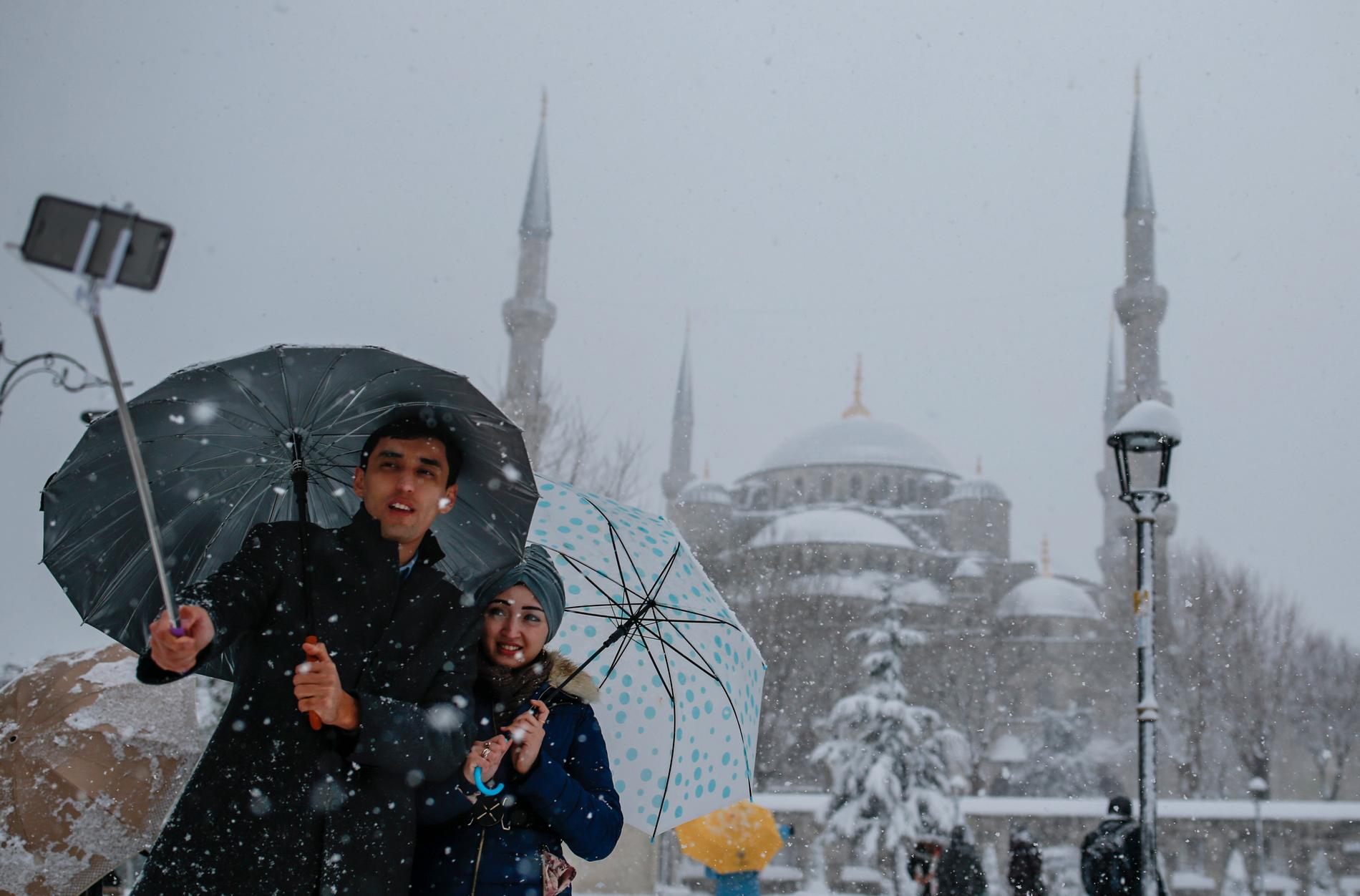 Ett par fotograferar sig framför den Blå moskén i Istanbul.