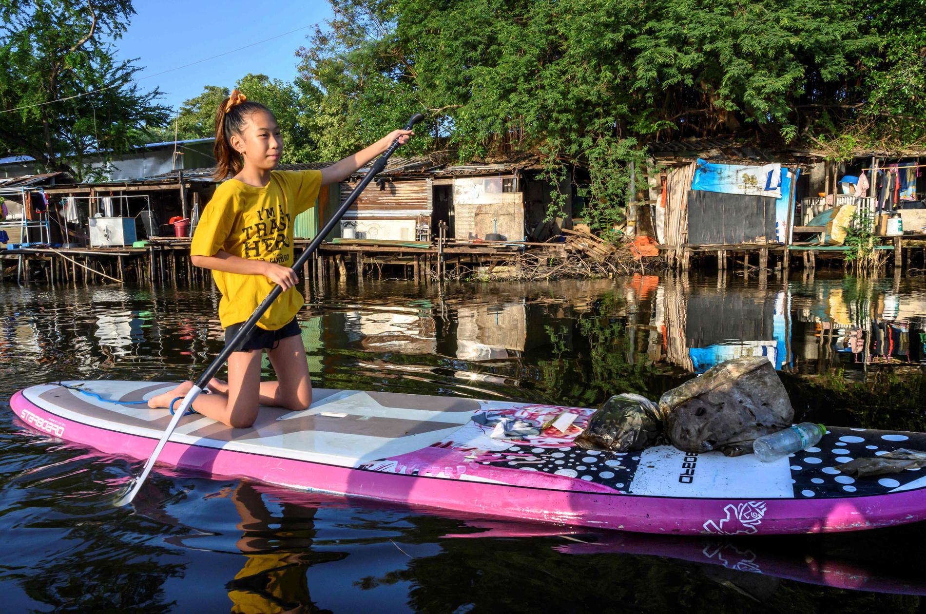 Tolvåriga Ralyn Satidtanasarn paddlar i Bangkok för att fiska upp skräp.