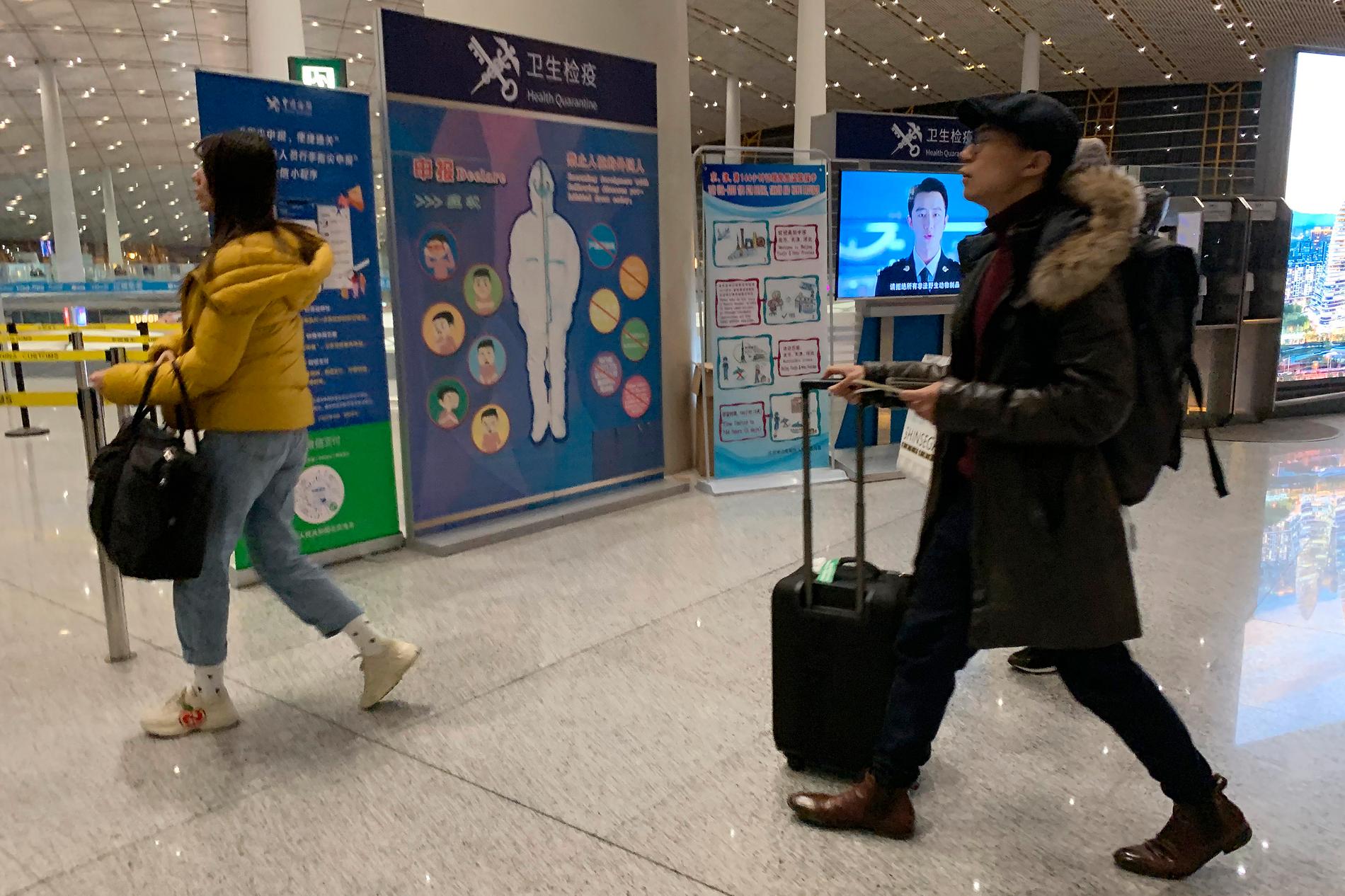 Resenärer passerar en hälsokontroll vid den internationella flygplatsen i Peking. Bilden togs den 13 januari.