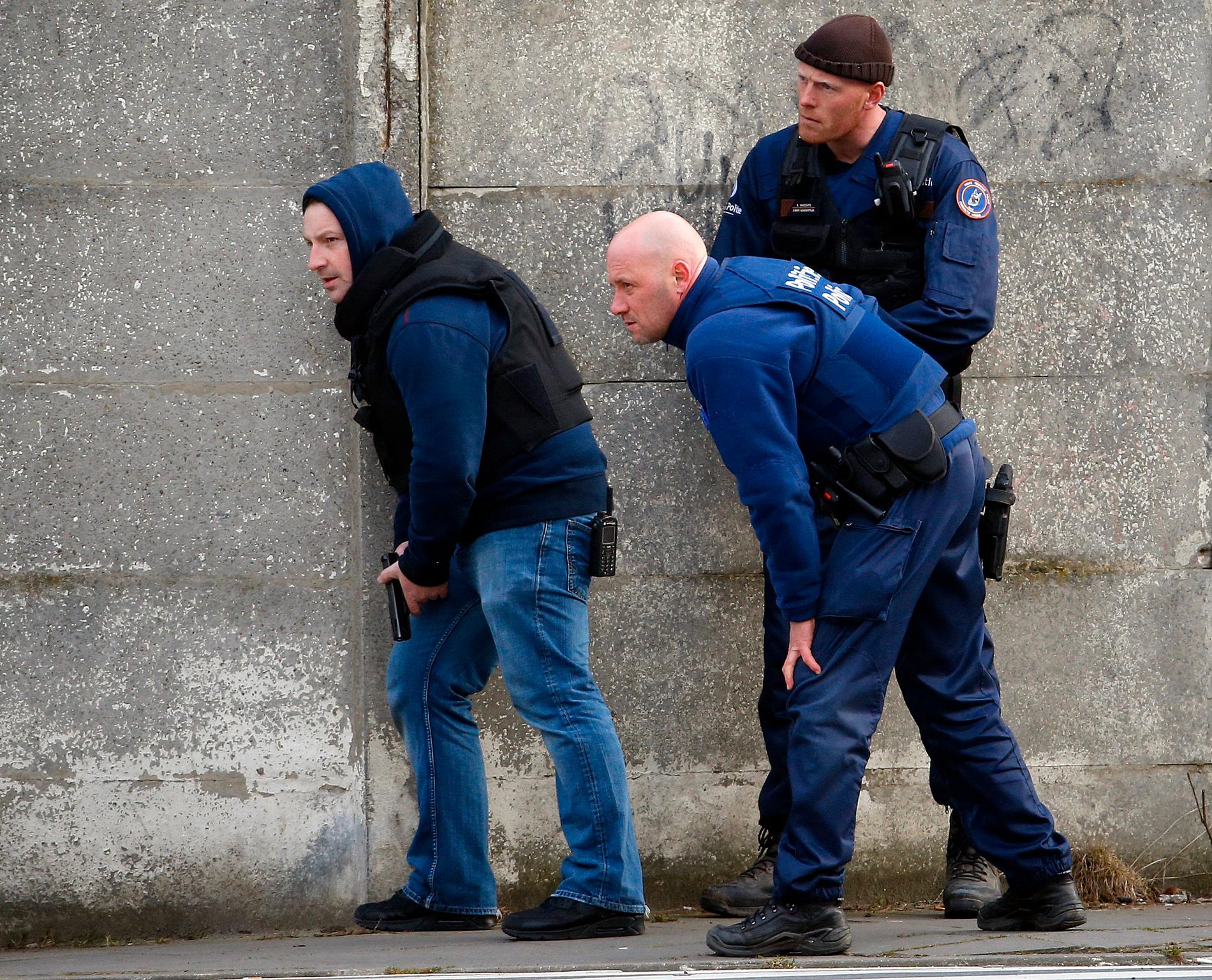 Poliser tar skydd i närheten av platsen där skottlossning bröt ut när polisen gjorde ett tillslag i förorten Forest nära Bryssel.