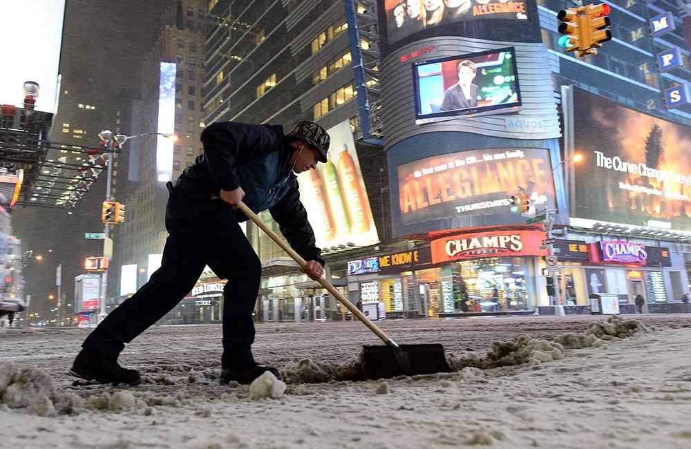 En man skottar snö vid Times Square på Manhattan.