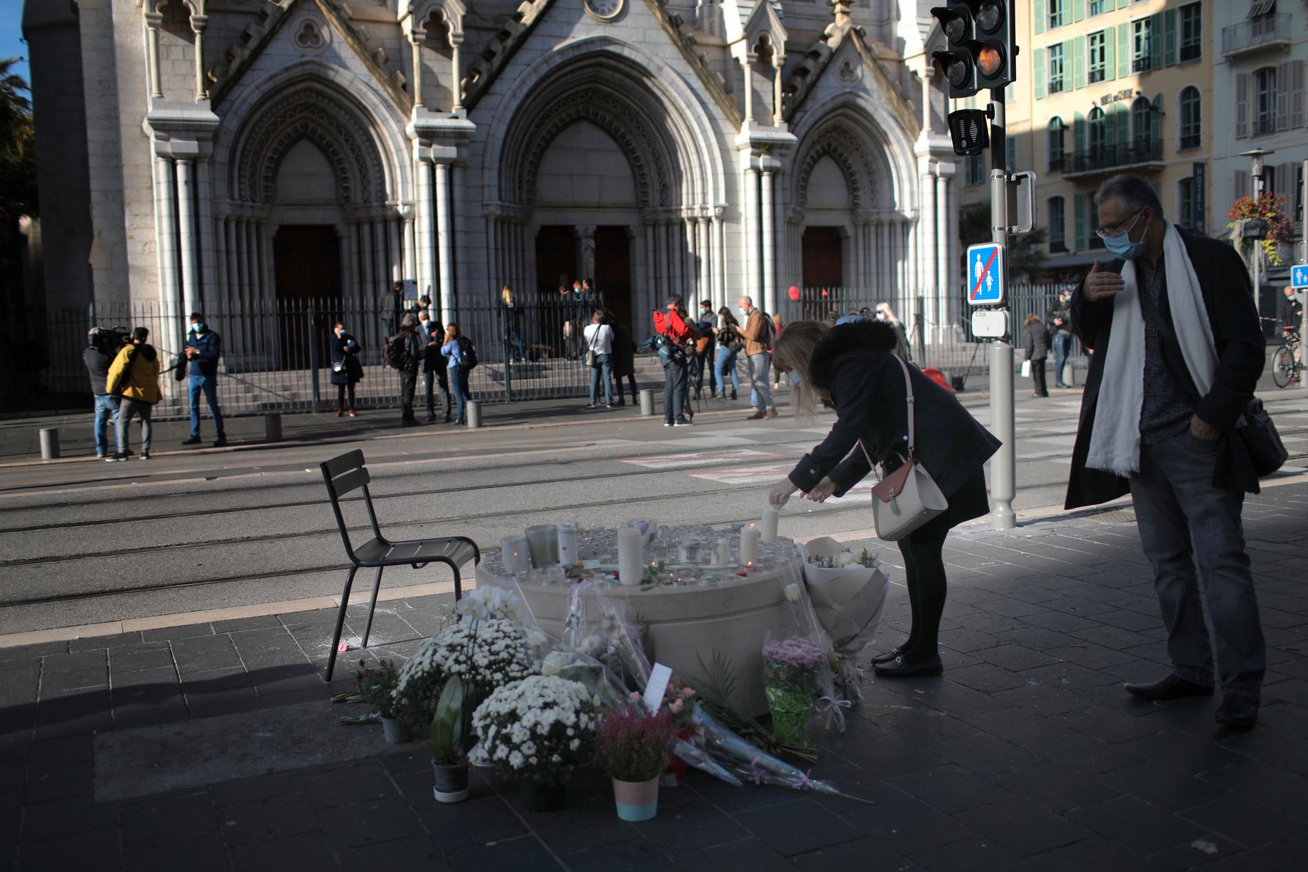 En kvinna tänder ett ljus utanför Notre Dame i Nice, dagen efter knivdådet som tog tre människors liv.