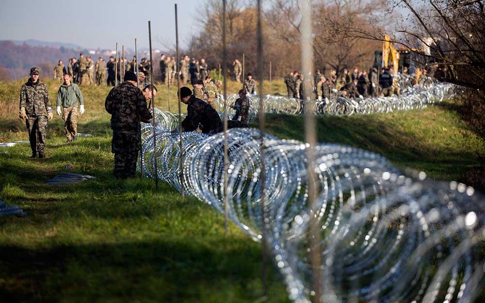 Slovensk militär placerar ut taggtråd vid gränsen mot Kroatien.