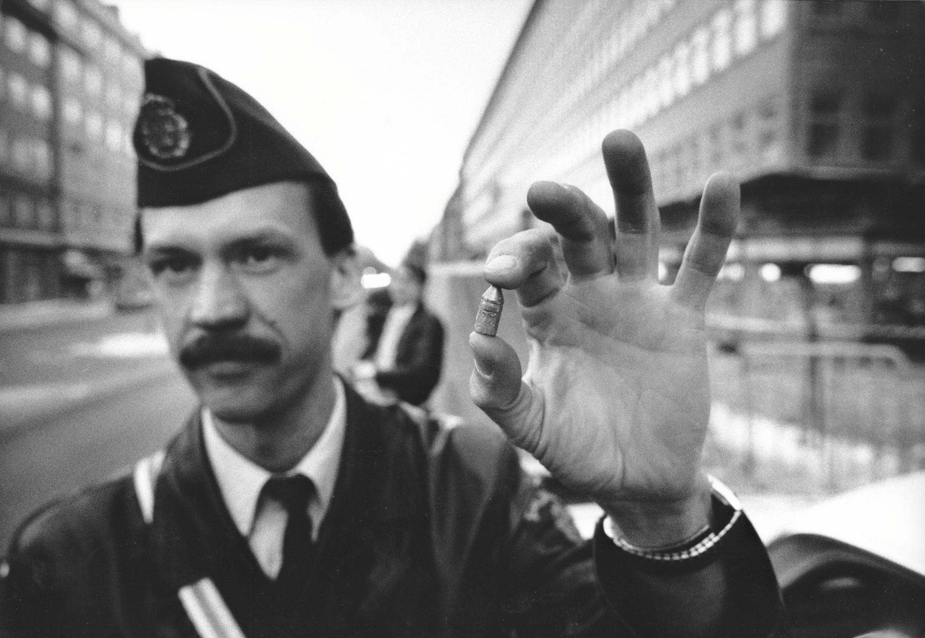 Polisinspektören Bo Larsson håller upp en grovkalibrig kula som hittades på trottoaren efter mordet på Olof Palme.