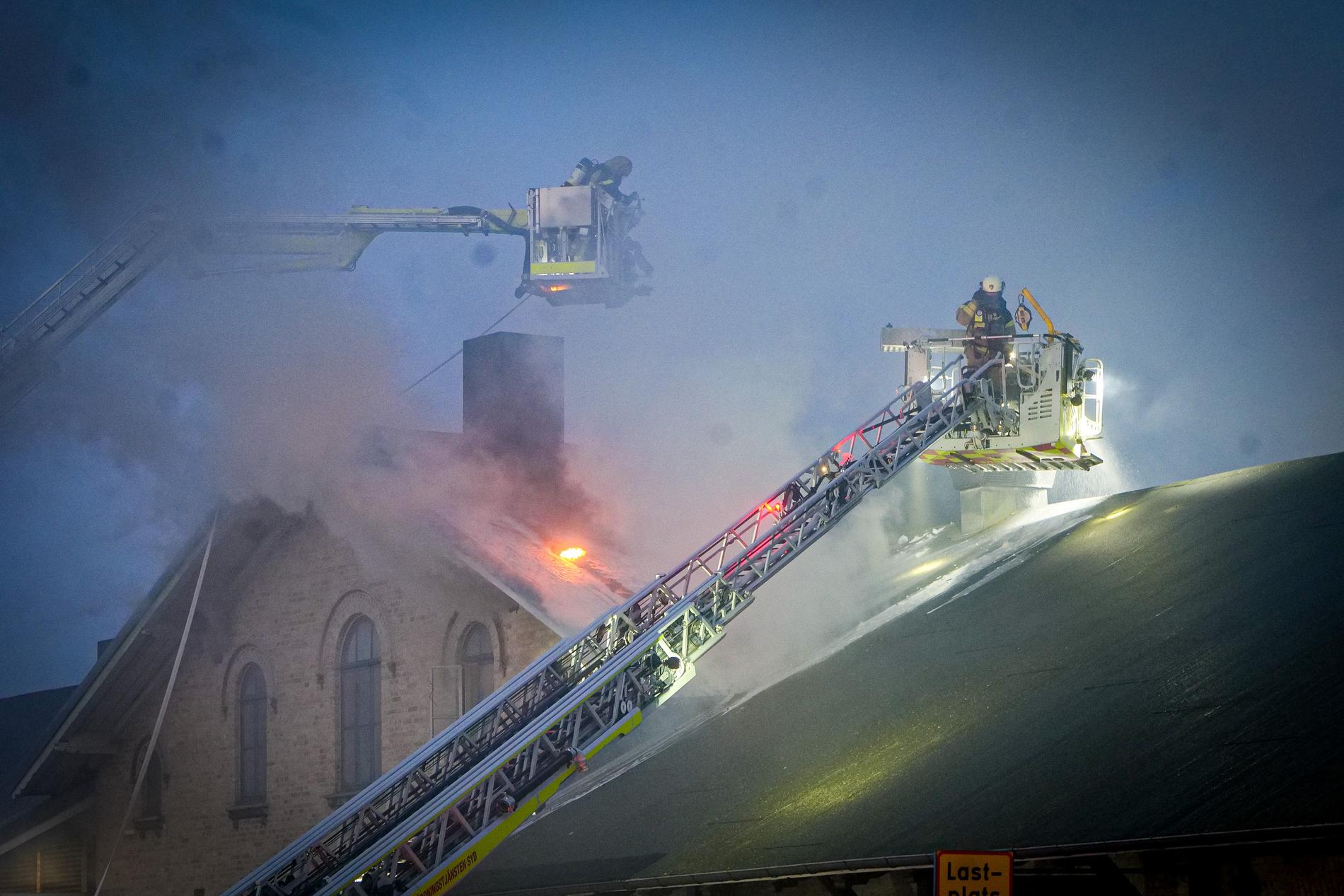 Räddningstjänsten släcker branden från luften med hävare.