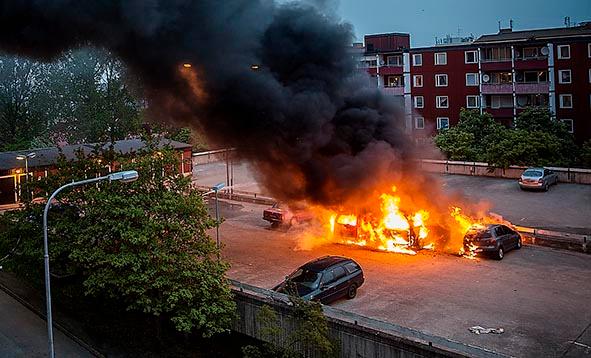 En brinnande bil under upploppen i Stockholmsförorten Husby 2013.