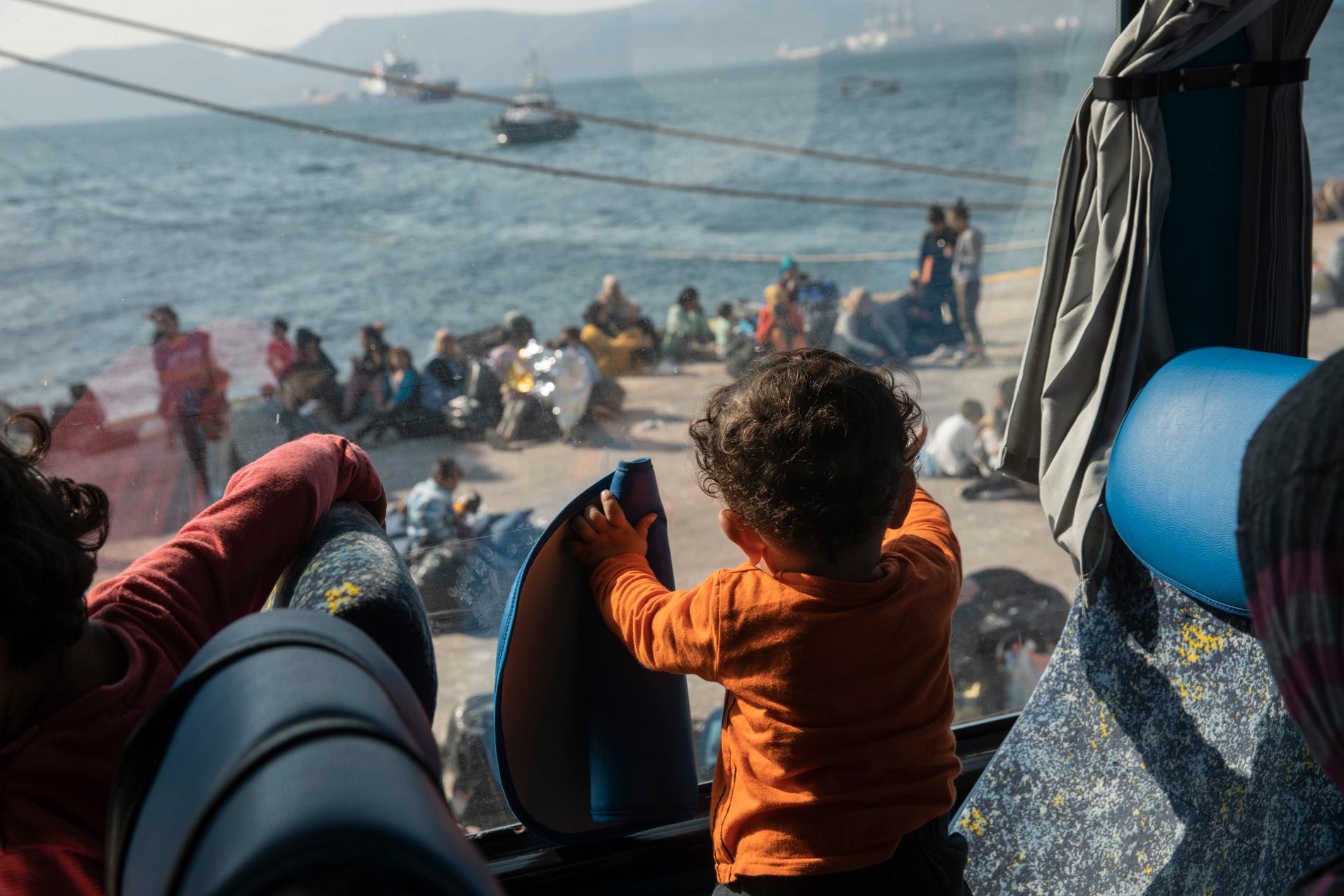 Ett barn från Syrien tittar ut genom fönstret på en buss sedan en grupp flyktingar och migranter anlänt till hamnen i Elefsina nära Greklands huvudstad Aten i tisdags. Rutten via Grekland in i EU har på senare tid återigen blivit allt vanligare för migranter.