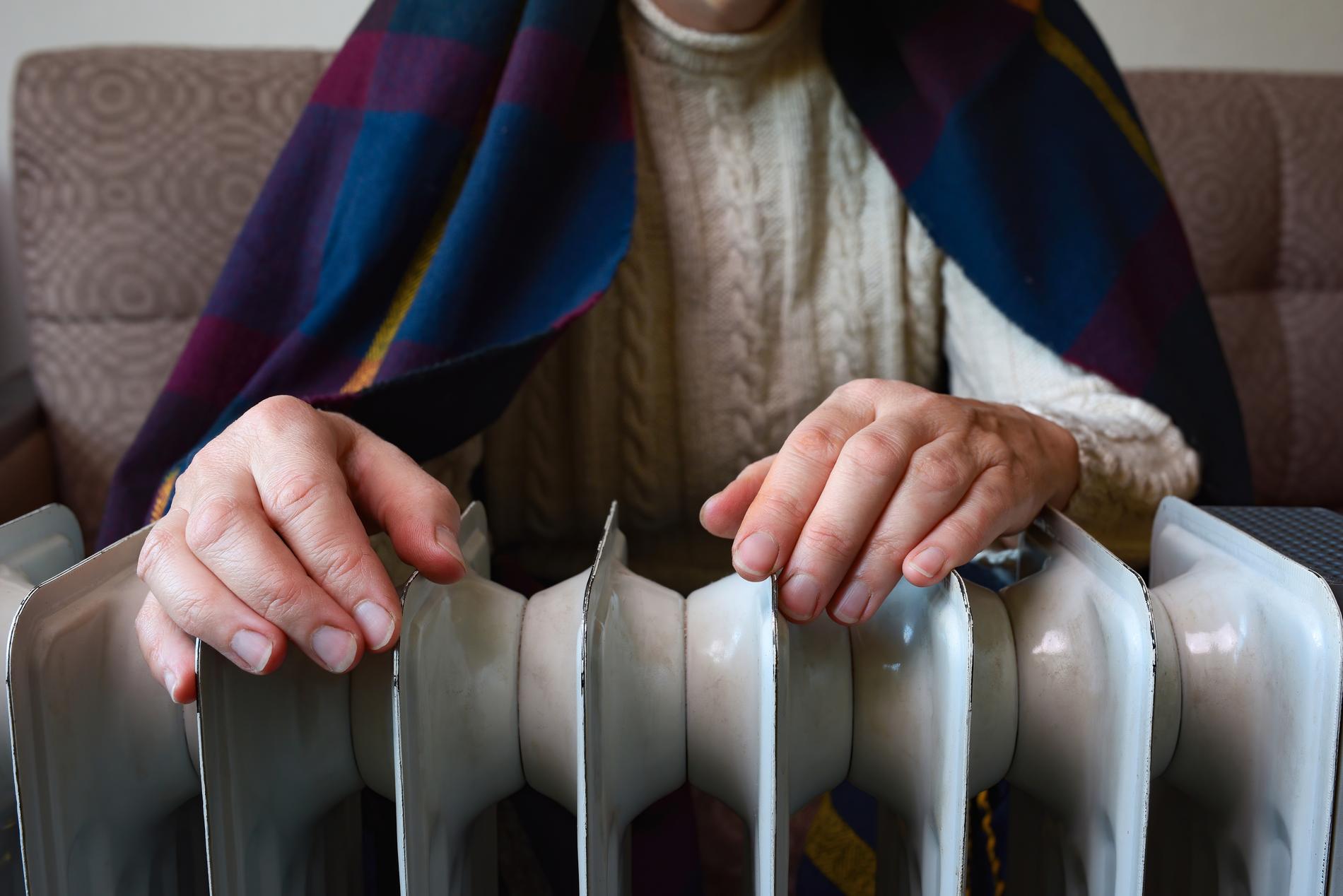 En kvinna med en filt över axlarna vilar händerna på ett element framför sig.