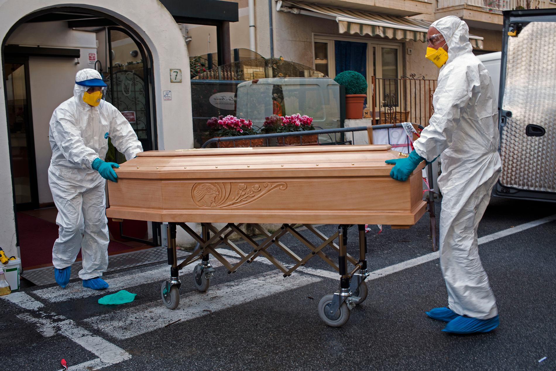 Medicinsk personal bär ut kistan för en person som avlidit i covid-19 i regionen Lombardiet i Italien. Arkivbild.