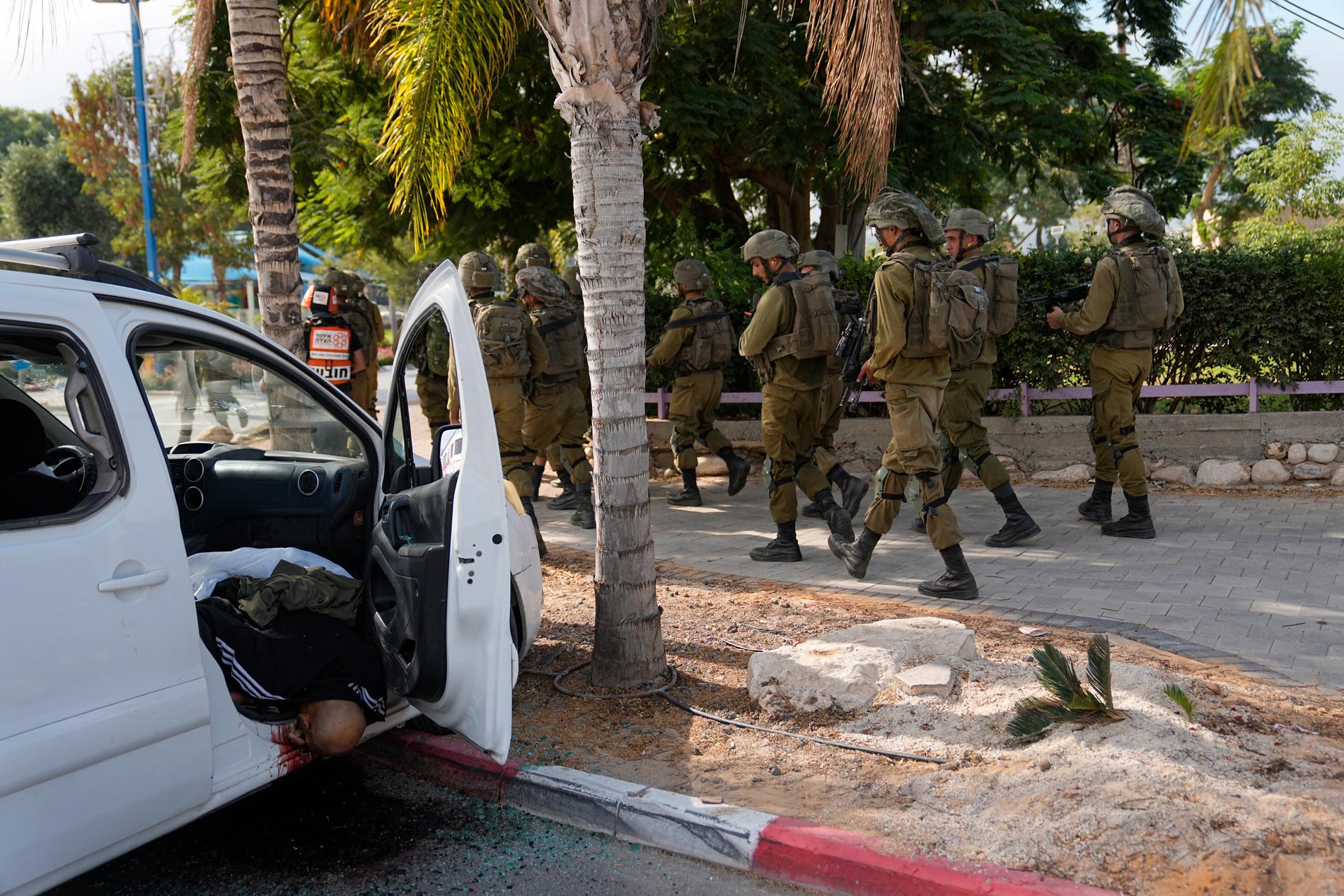 Israeliska soldater går förbi en person som dödats av Hamasstyrkor i Sderot, Israel, den 7 oktober, 2023.