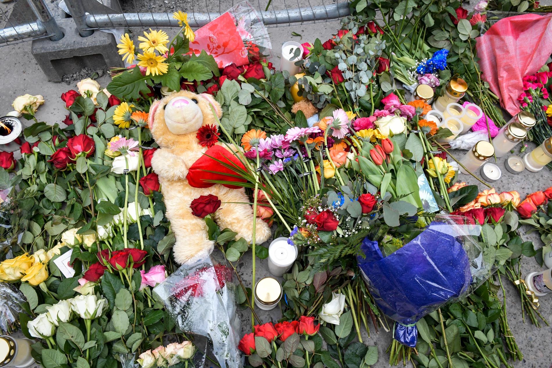 Blommor, ljus och en nalle vid Åhléns i centrala Stockholm efter terrordådet på Drottninggatan för två år sedan.