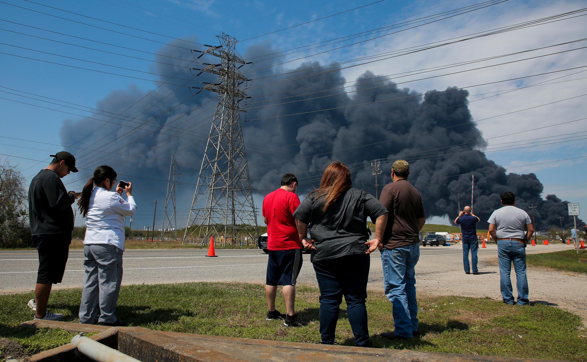 Personer i Houston, Texas samlas för att titta på rökmolnet som stiger från branden i ett företags lagringslokaler i staden.