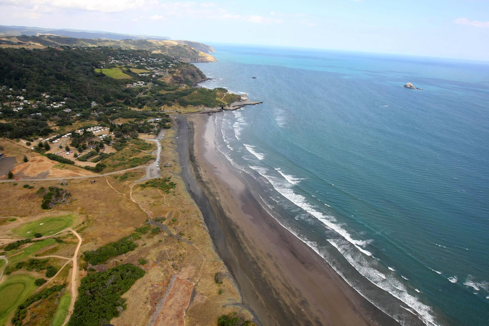 Stranden Muriwai utanför Auckland i norra Nya Zeeland, dit ofarliga vågor från söndagens skalv kan nå. Arkivbild.